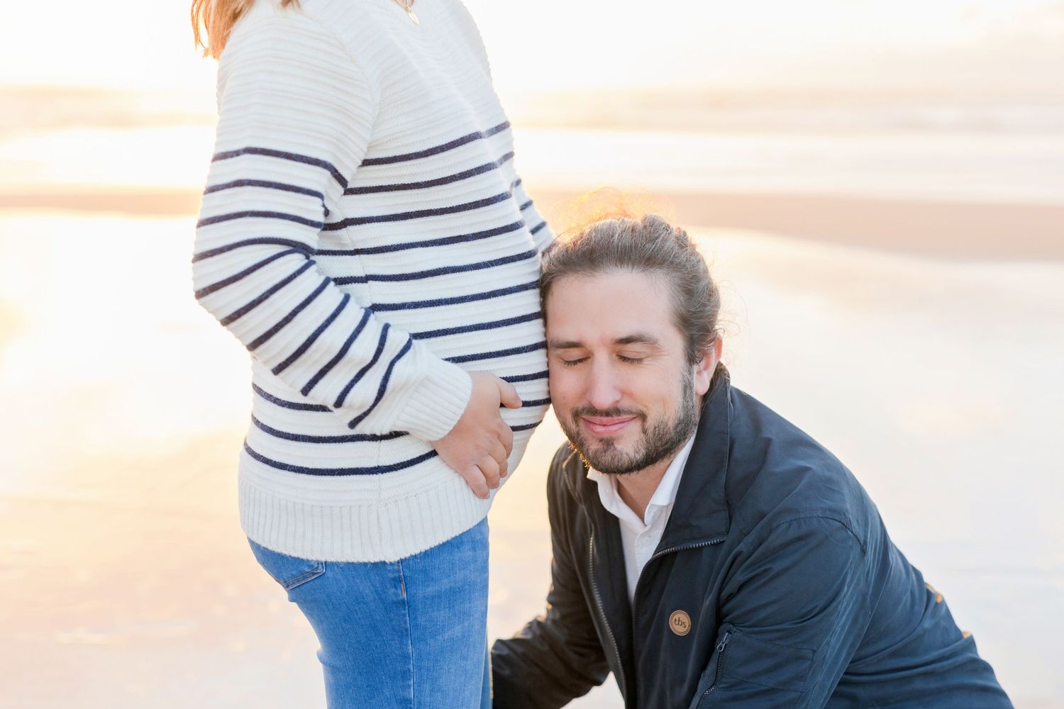 Candid beach moment between couple wearing nautical-inspired clothing.