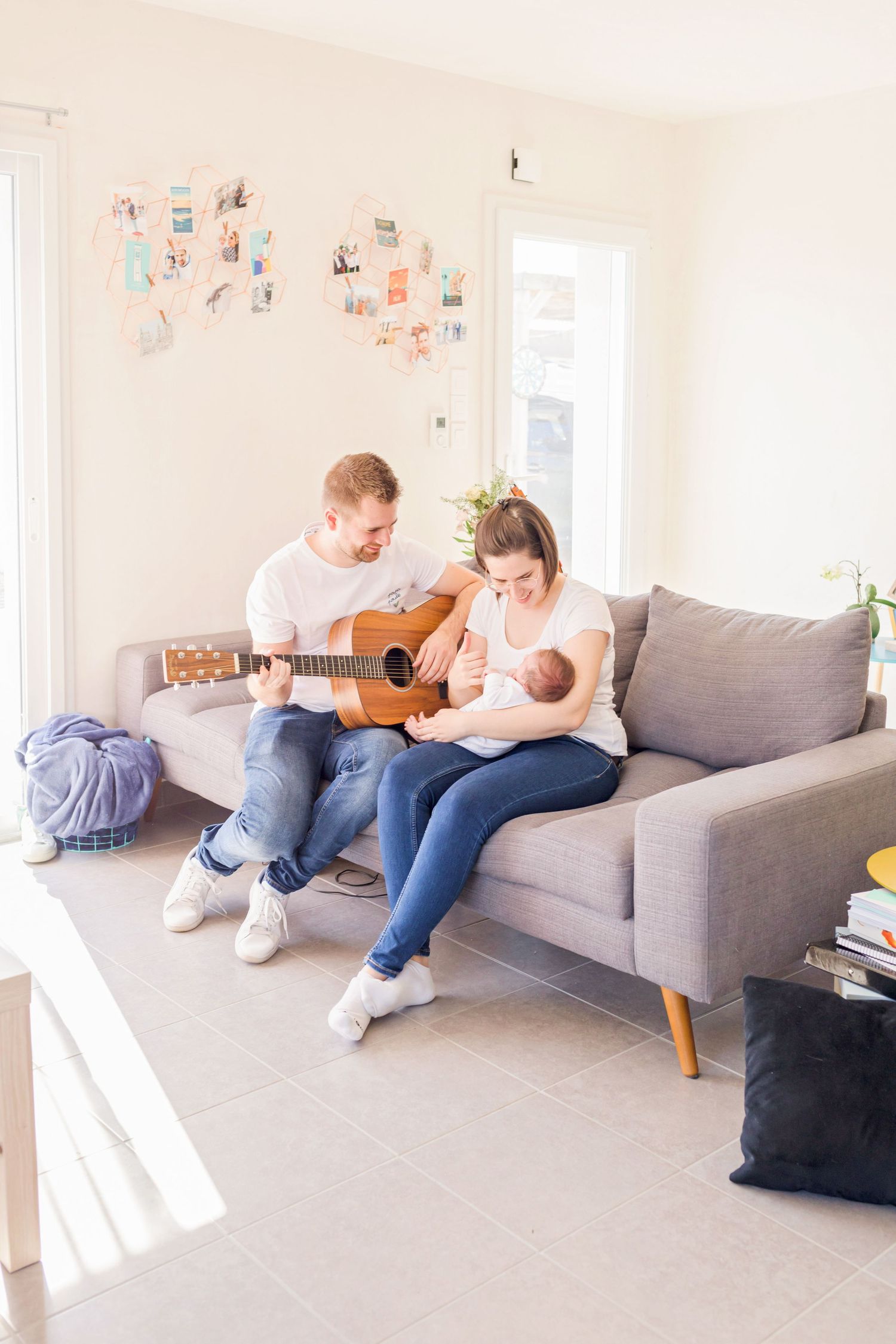 Wide angle view of a bright living room with family sharing musical moments on a grey sofa.