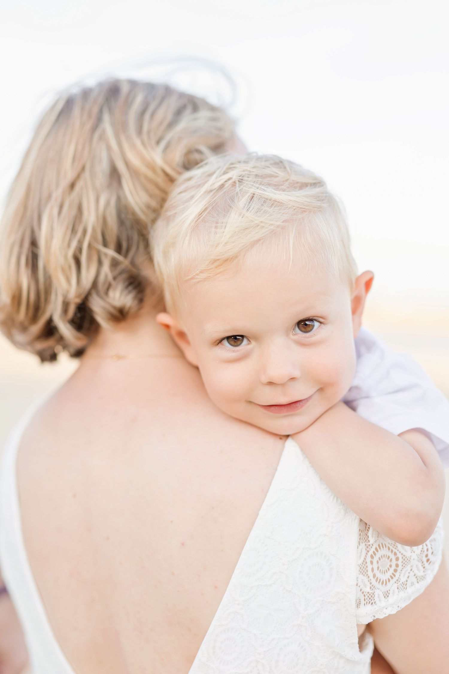 Sun-kissed family portrait with soft white background showing gentle affection.