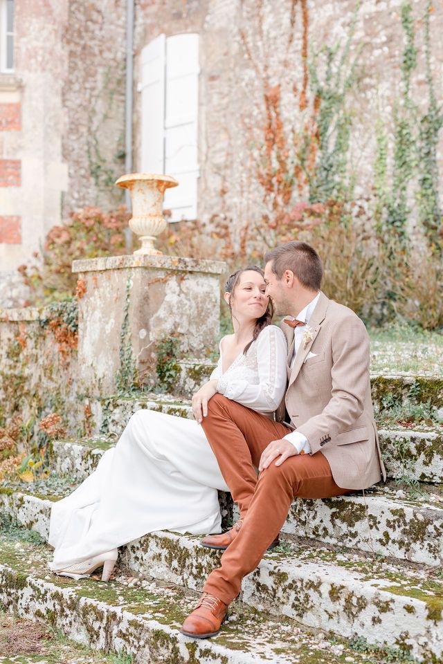 Couple sharing an intimate moment on moss-covered stone steps of a historic French chateau.
