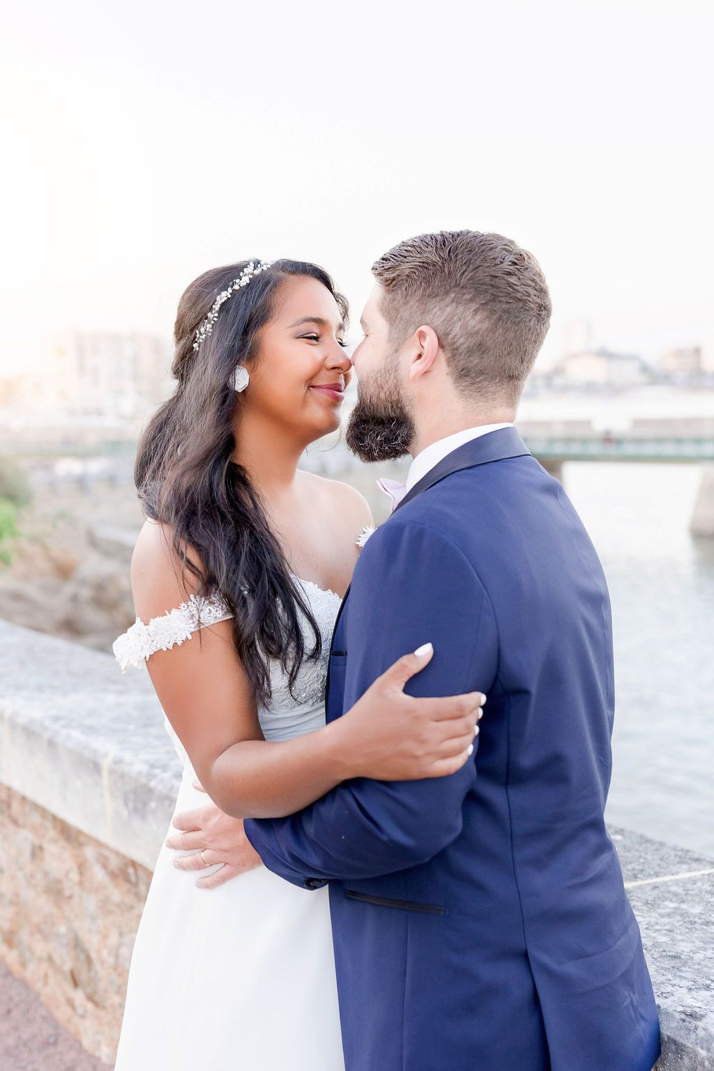 Newlyweds share a tender embrace on a seaside promenade during their wedding photoshoot.