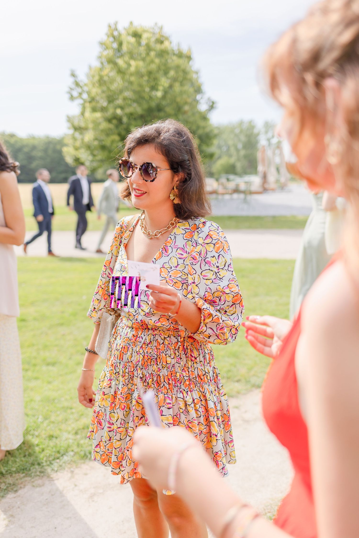 Garden party scene with guests mingling outdoors on a sunny summer day.