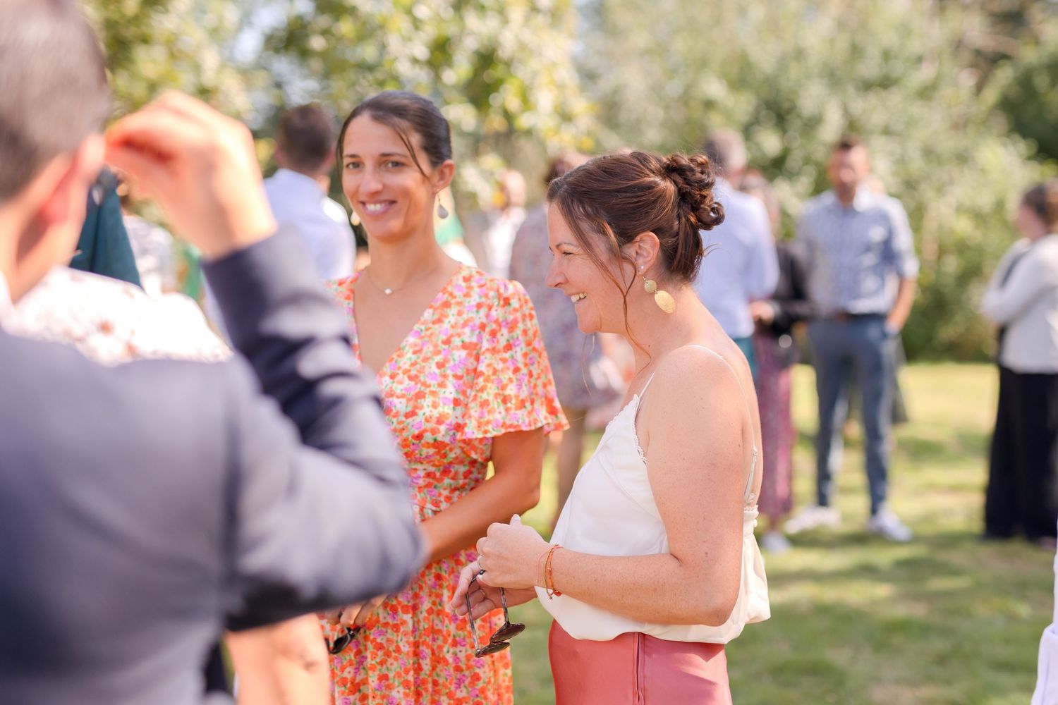 Outdoor wedding celebration with guests mingling in a sunny garden setting.