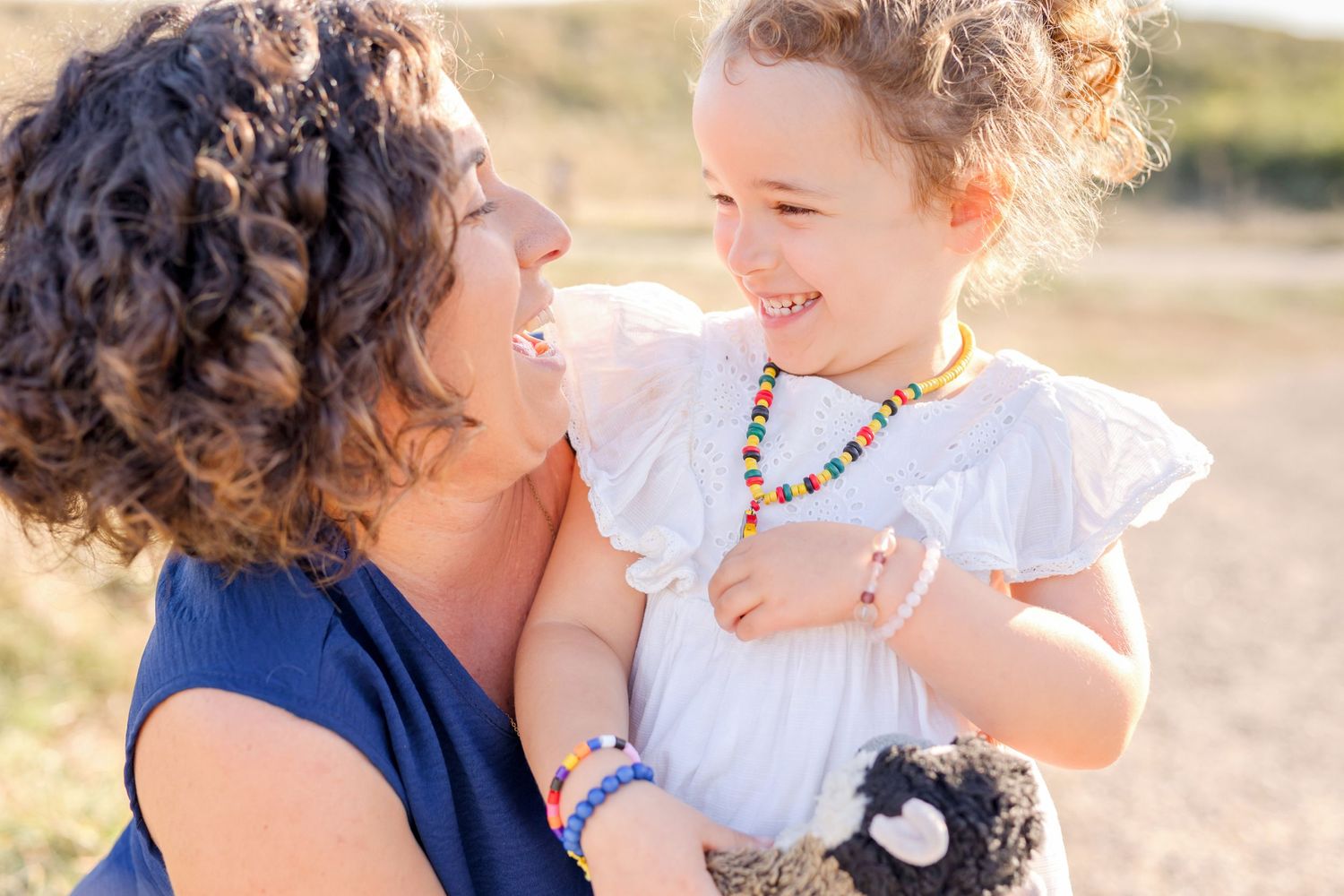 A joyful outdoor family moment captured in golden sunlight with a blue and white color scheme.
