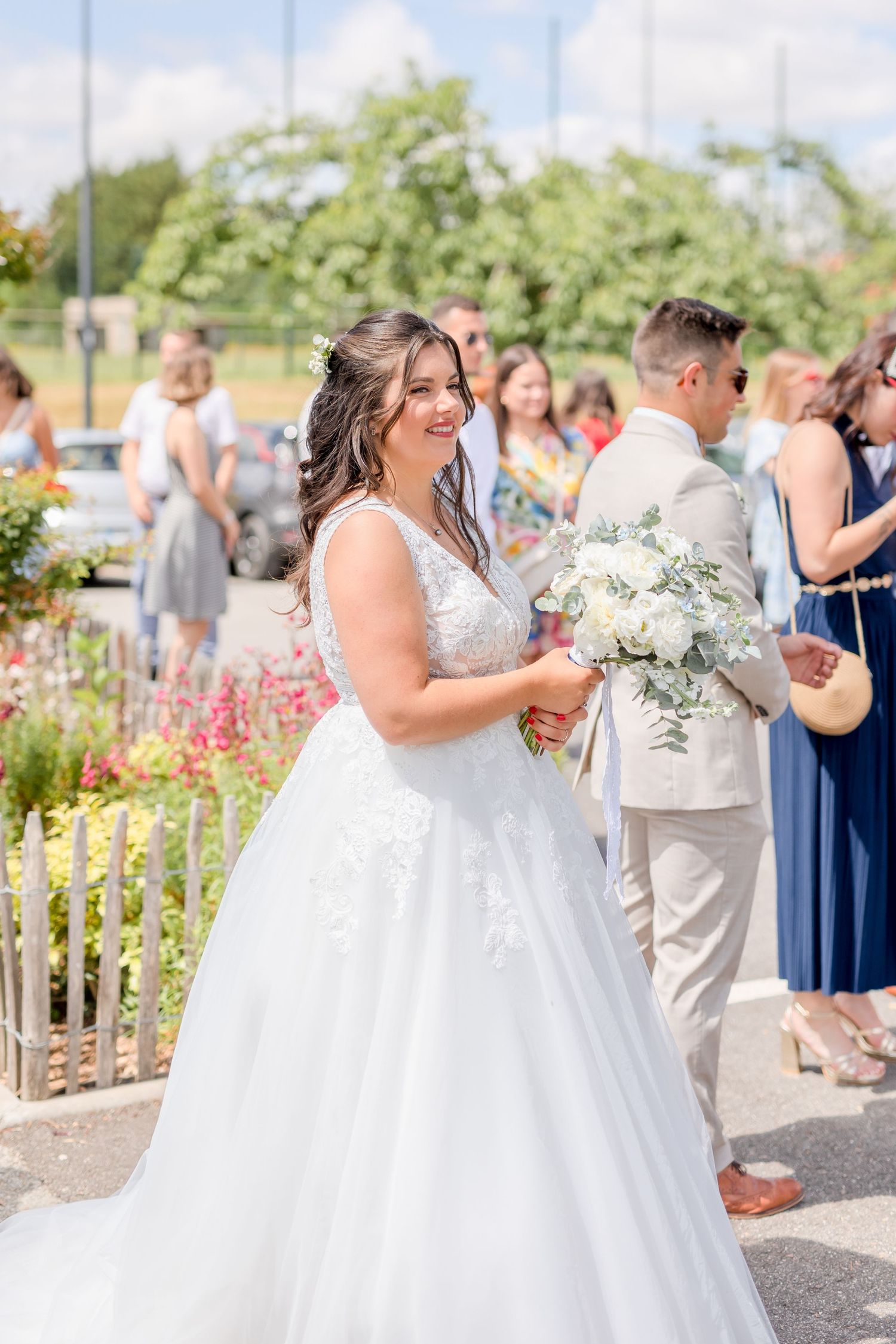 Wedding couple dancing and celebrating during a sunny outdoor reception with lush greenery in background.