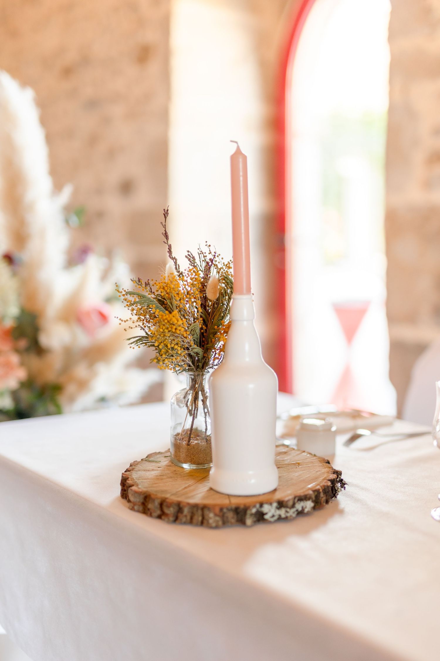Wedding table decorations with white candles and dried flowers on wooden slices.