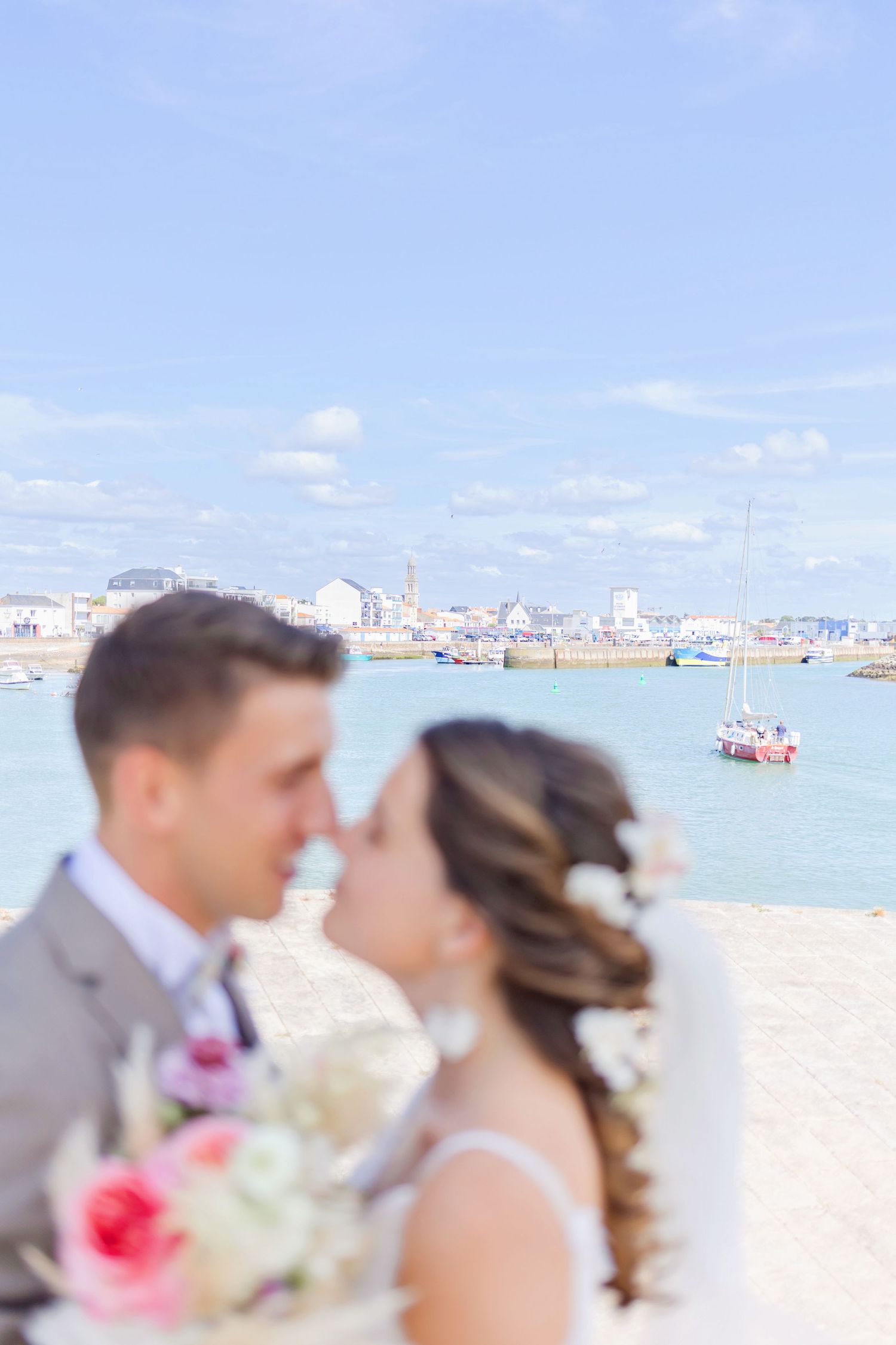 Romantic waterfront wedding portrait with city skyline and boats in background.