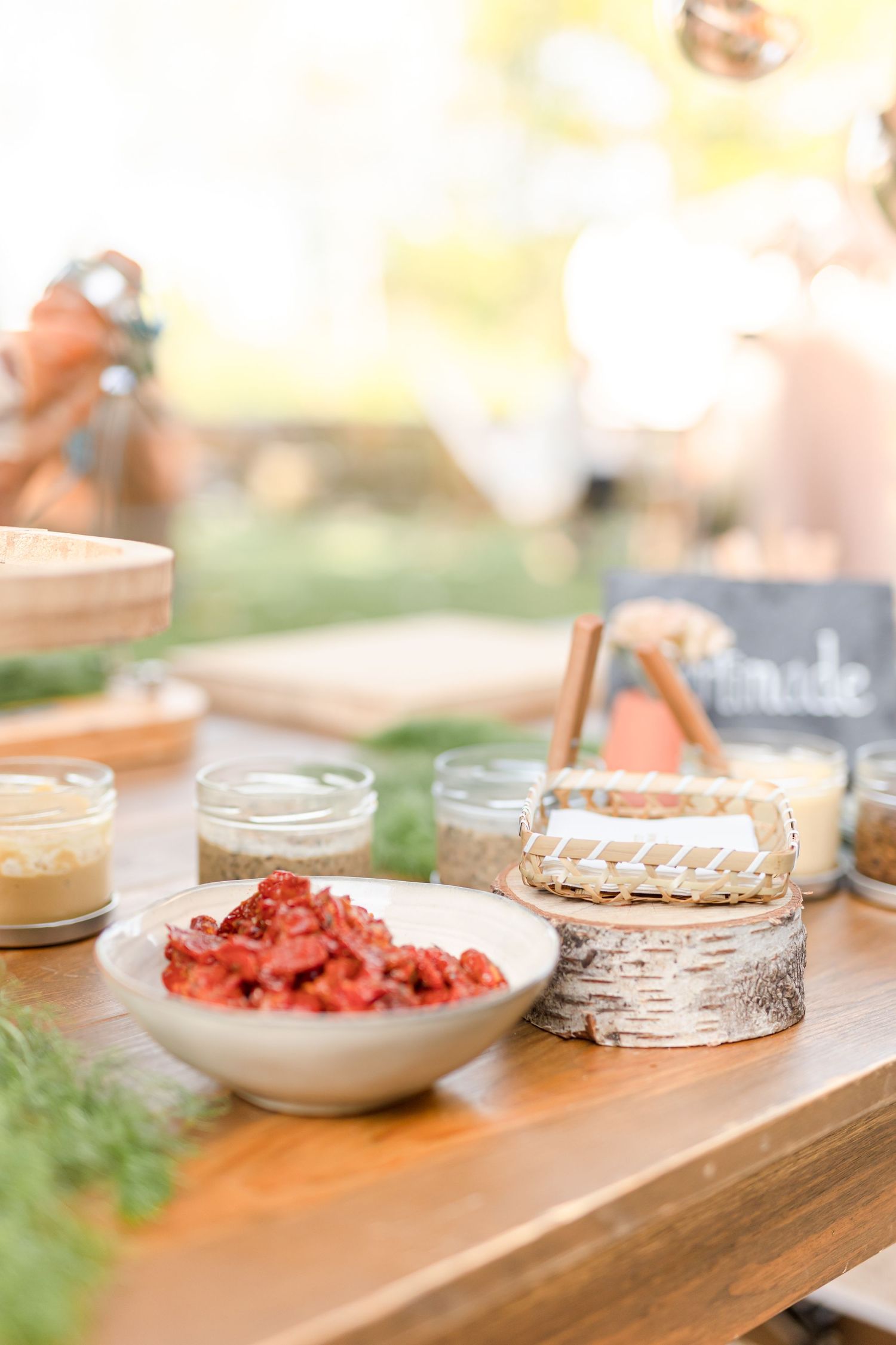 Wood table display of appetizers and small bites with decorative glass jars.