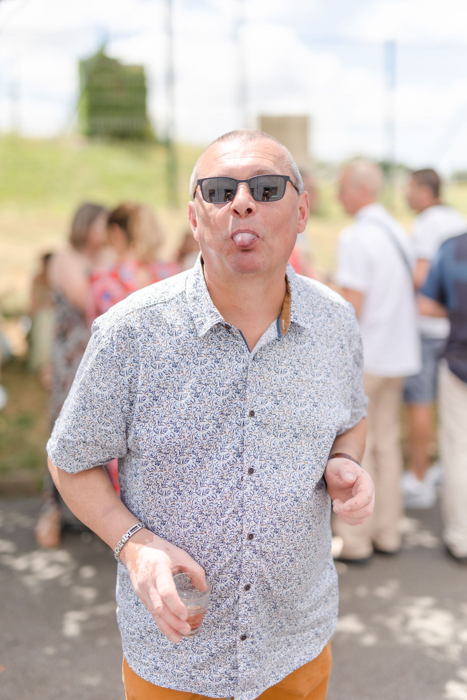 Casual party guest in gray shirt making playful expression at outdoor event.