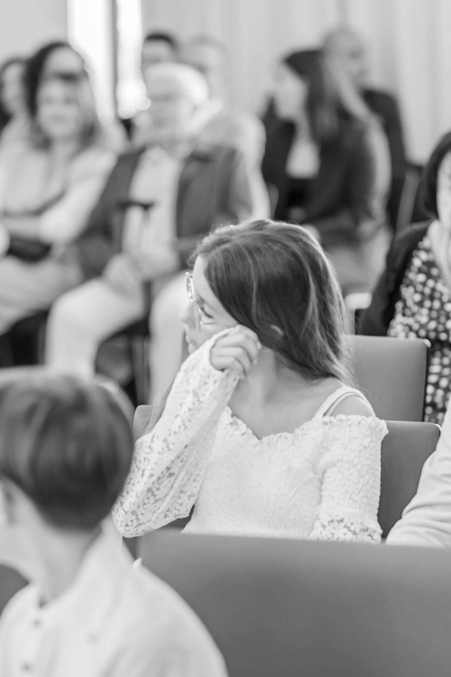 Guest at a wedding ceremony sits thoughtfully in a lace dress during the gathering.