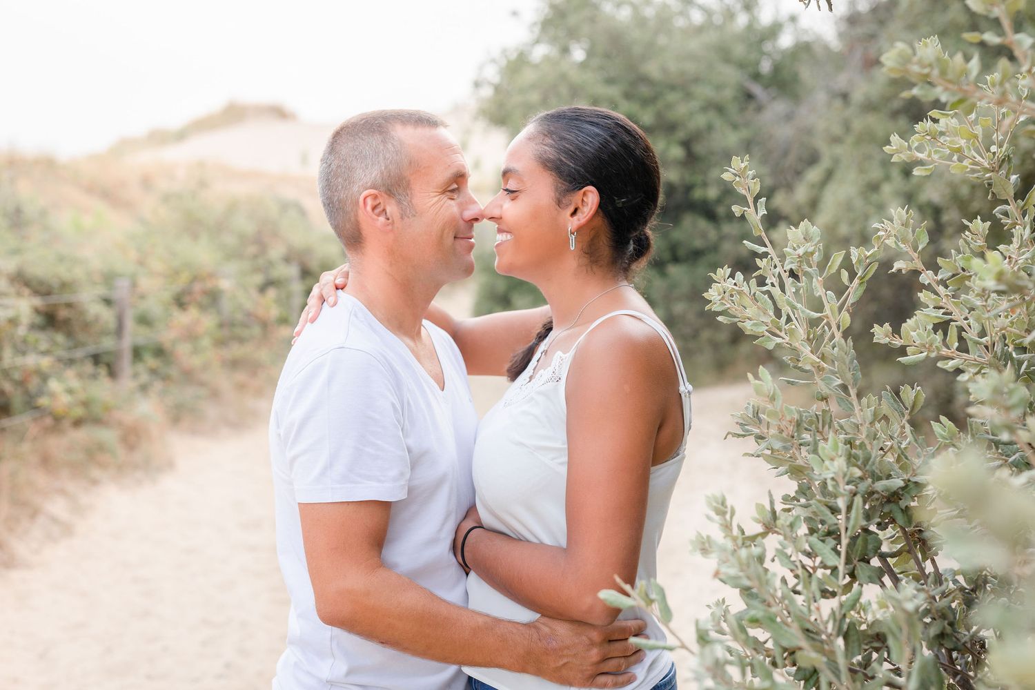 Affectionate couple sharing playful moments during outdoor photo session on desert trail.