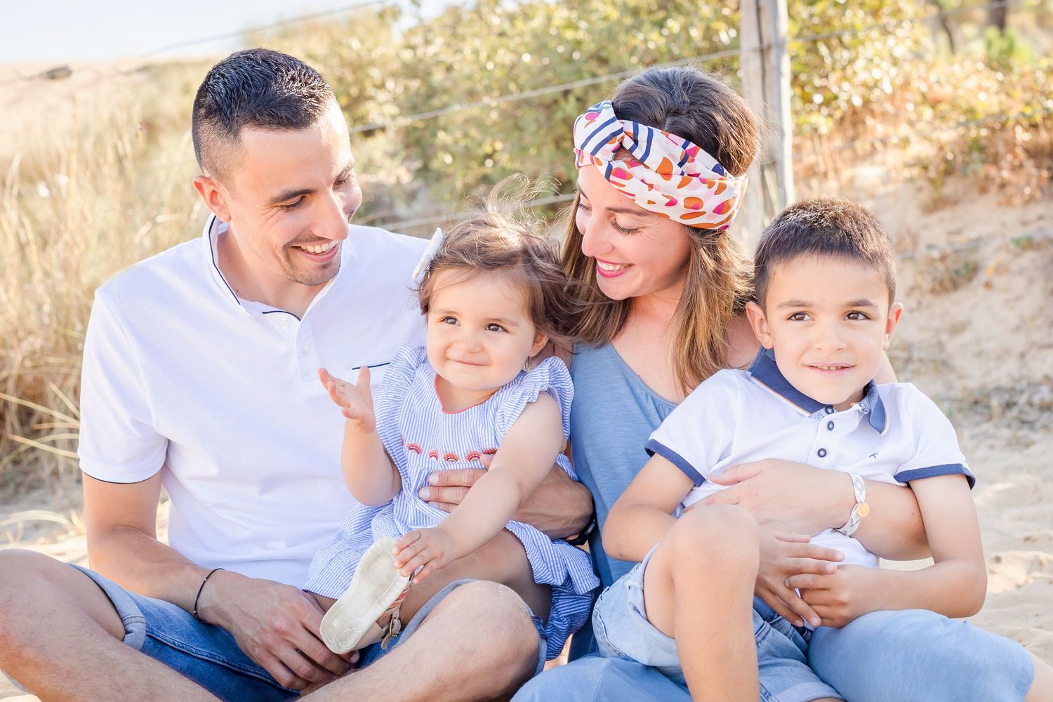 Casual family portrait session on beach dunes with matching outfits.