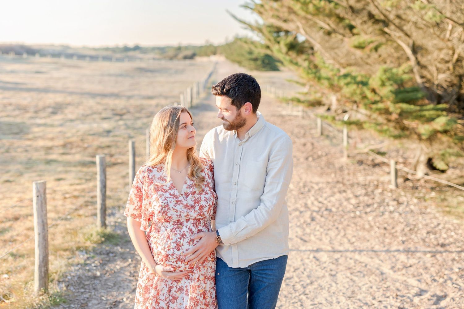 Expecting couple sharing an intimate moment on a nature trail during golden hour.