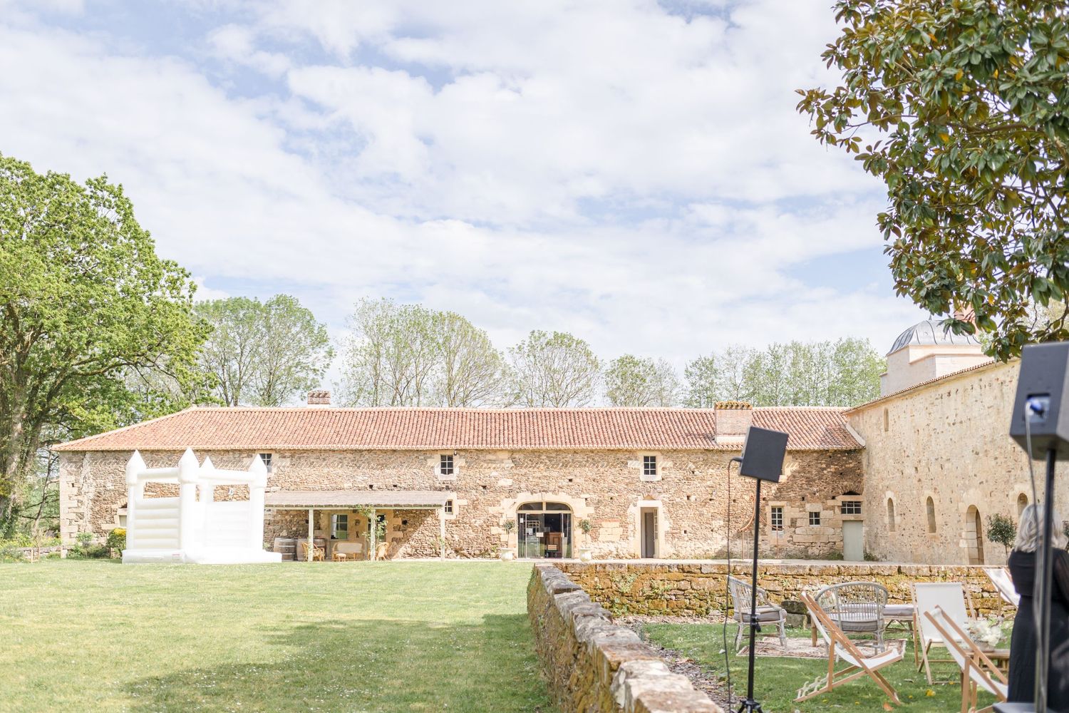 Panoramic view of a historic stone estate with expansive grounds under cloudy skies.