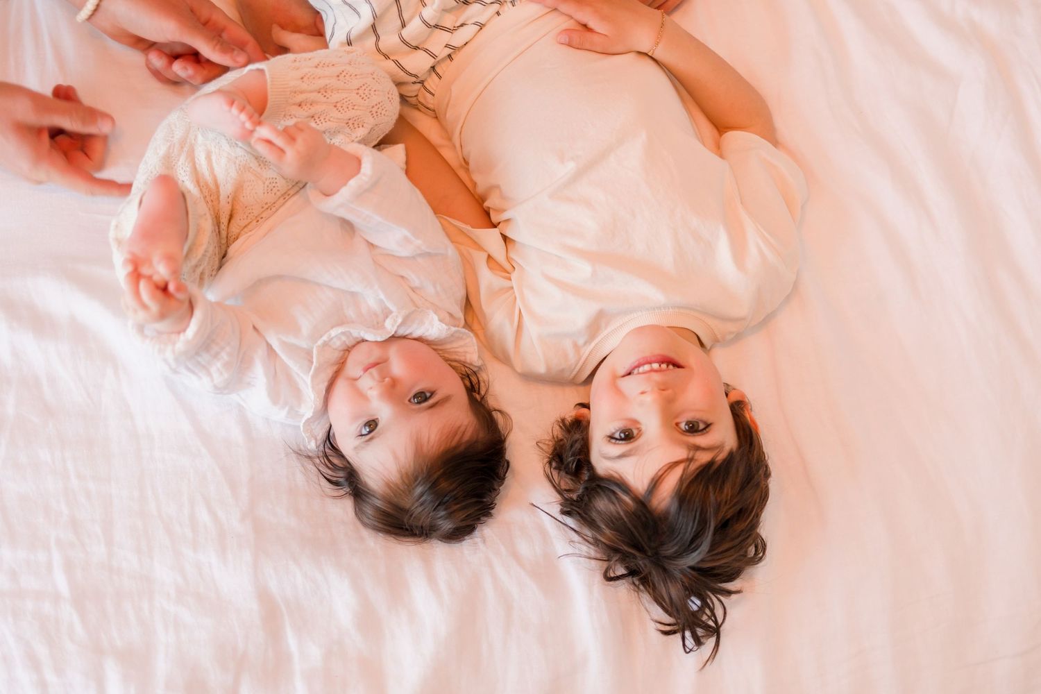Family members resting on white bedding with warm lighting creating a cozy atmosphere.