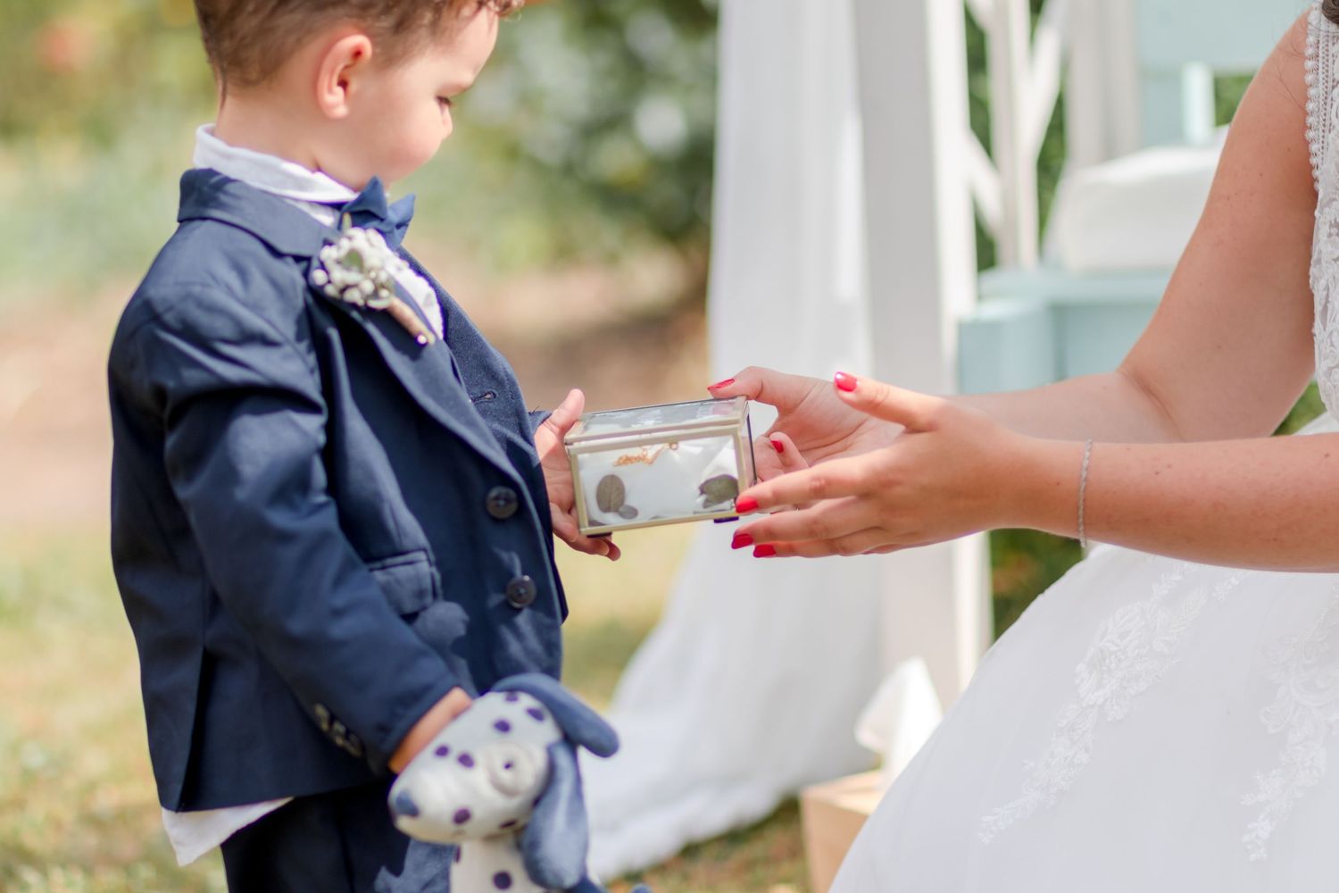 Small child in navy suit receives a gift during wedding ceremony.
