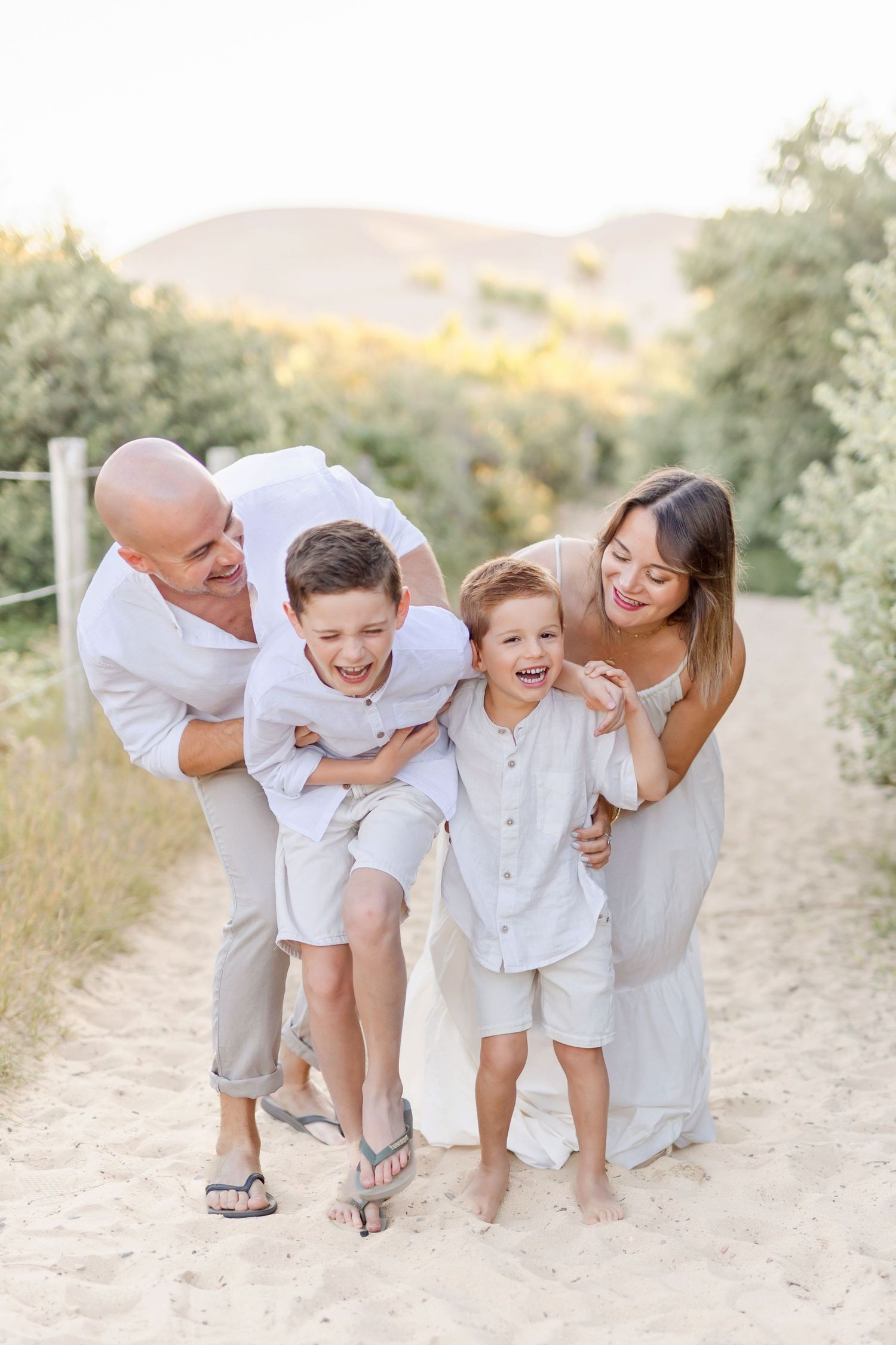 Candid family laughter shared on coastal trail during sunset.