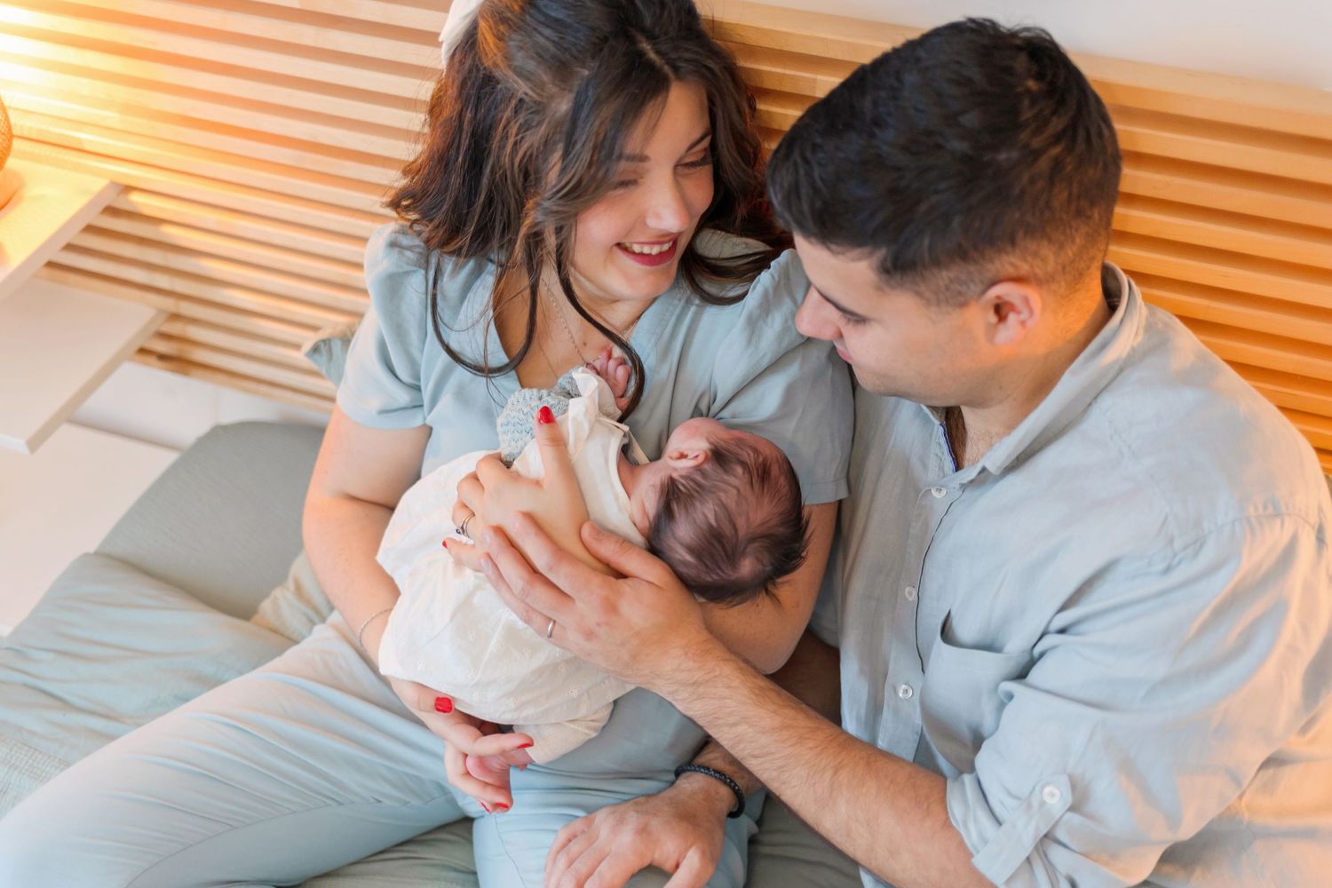 Parents sharing tender moment with their newborn baby in cozy setting.