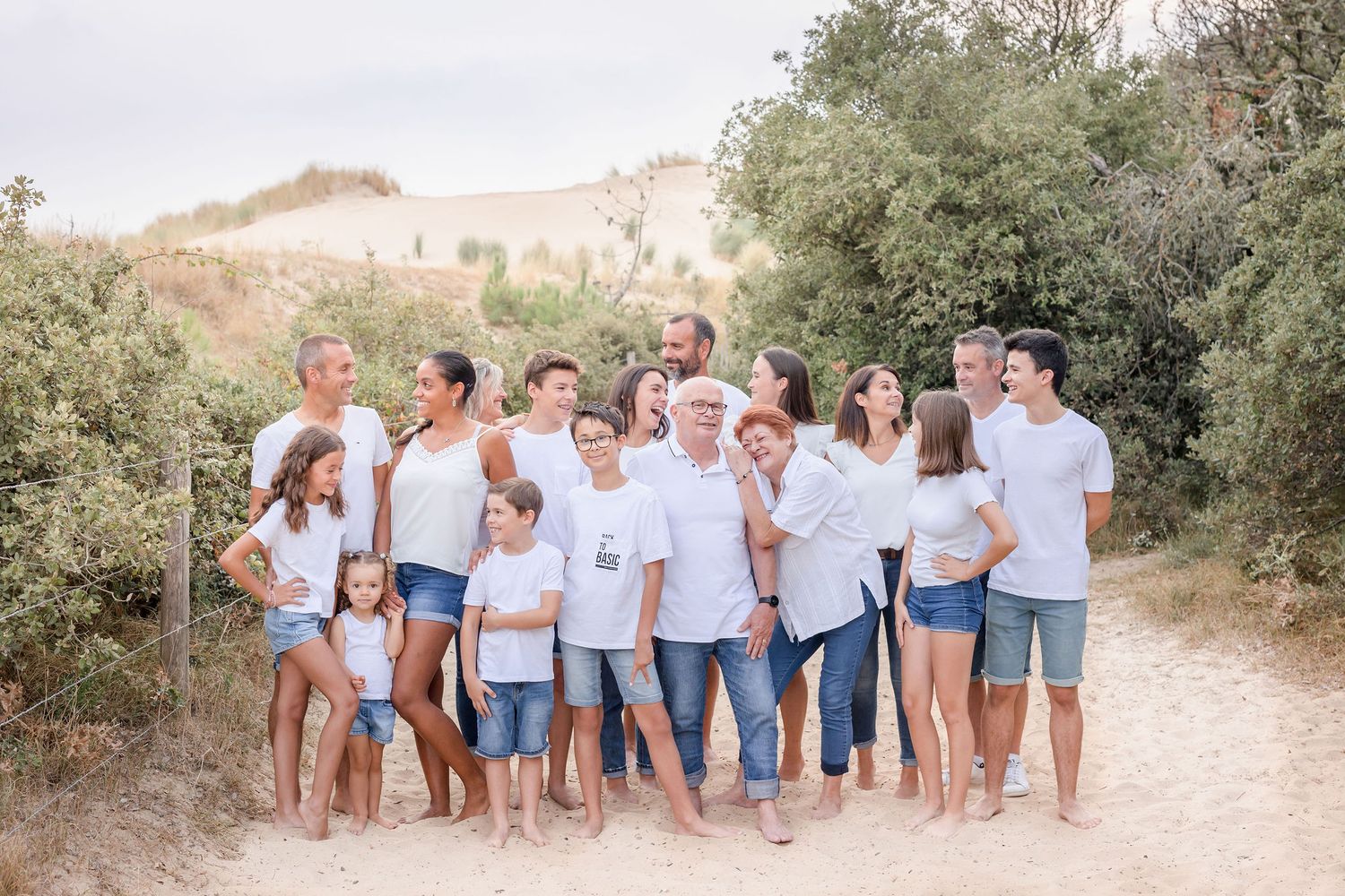 Extended family wearing matching casual outfits smiles together on outdoor trail.