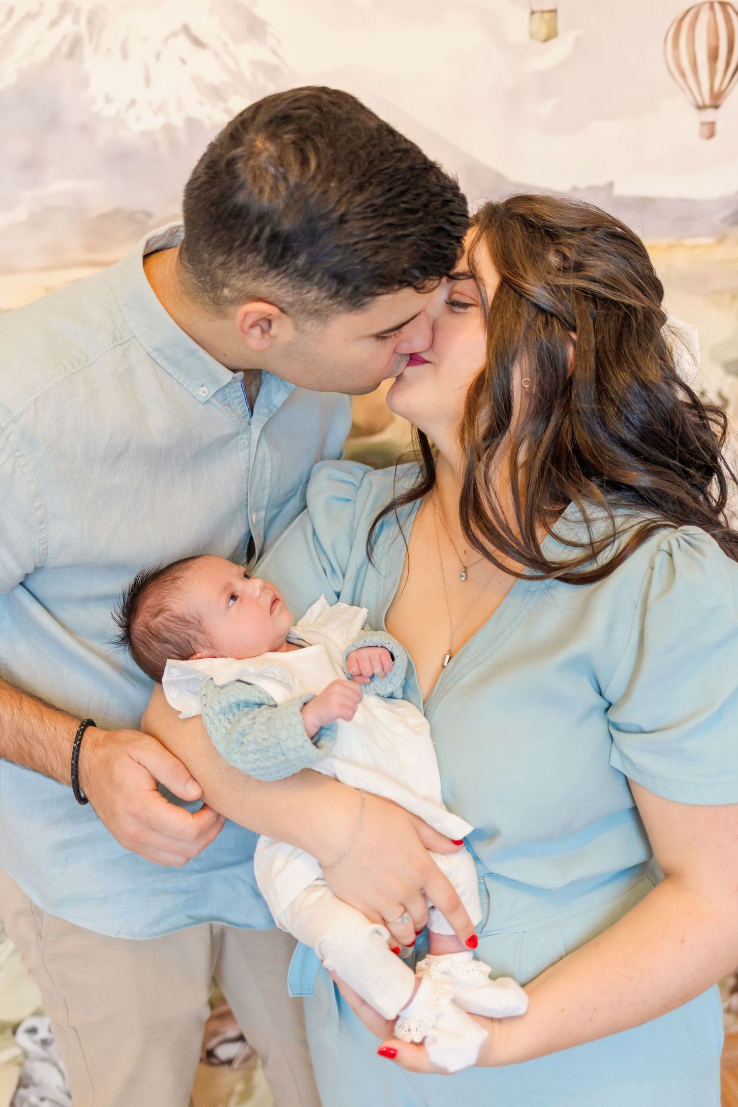An intimate family moment captured against a dreamy safari-themed wall with hot air balloons.