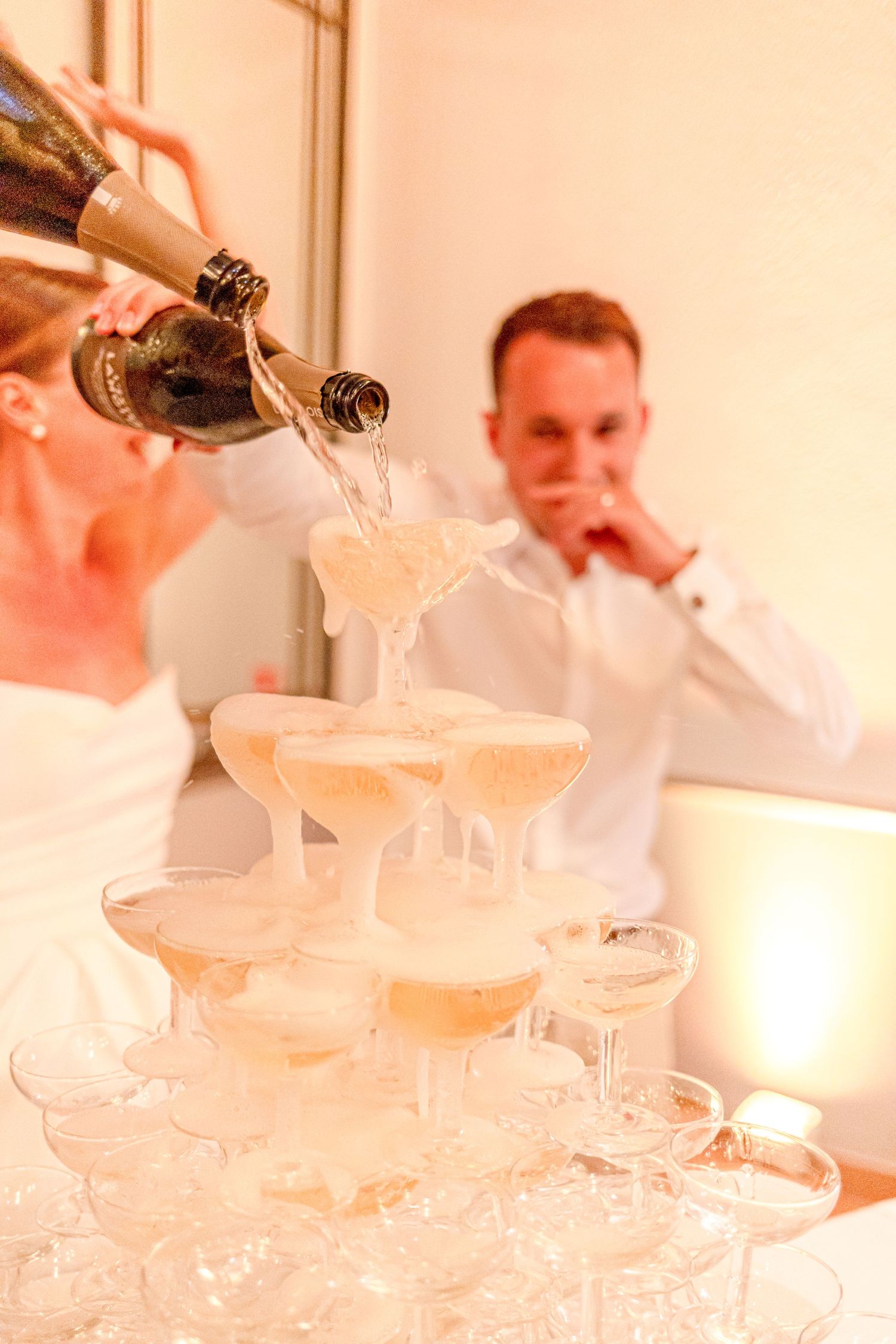 Champagne cascading down crystal glasses in a tower formation at wedding celebration.