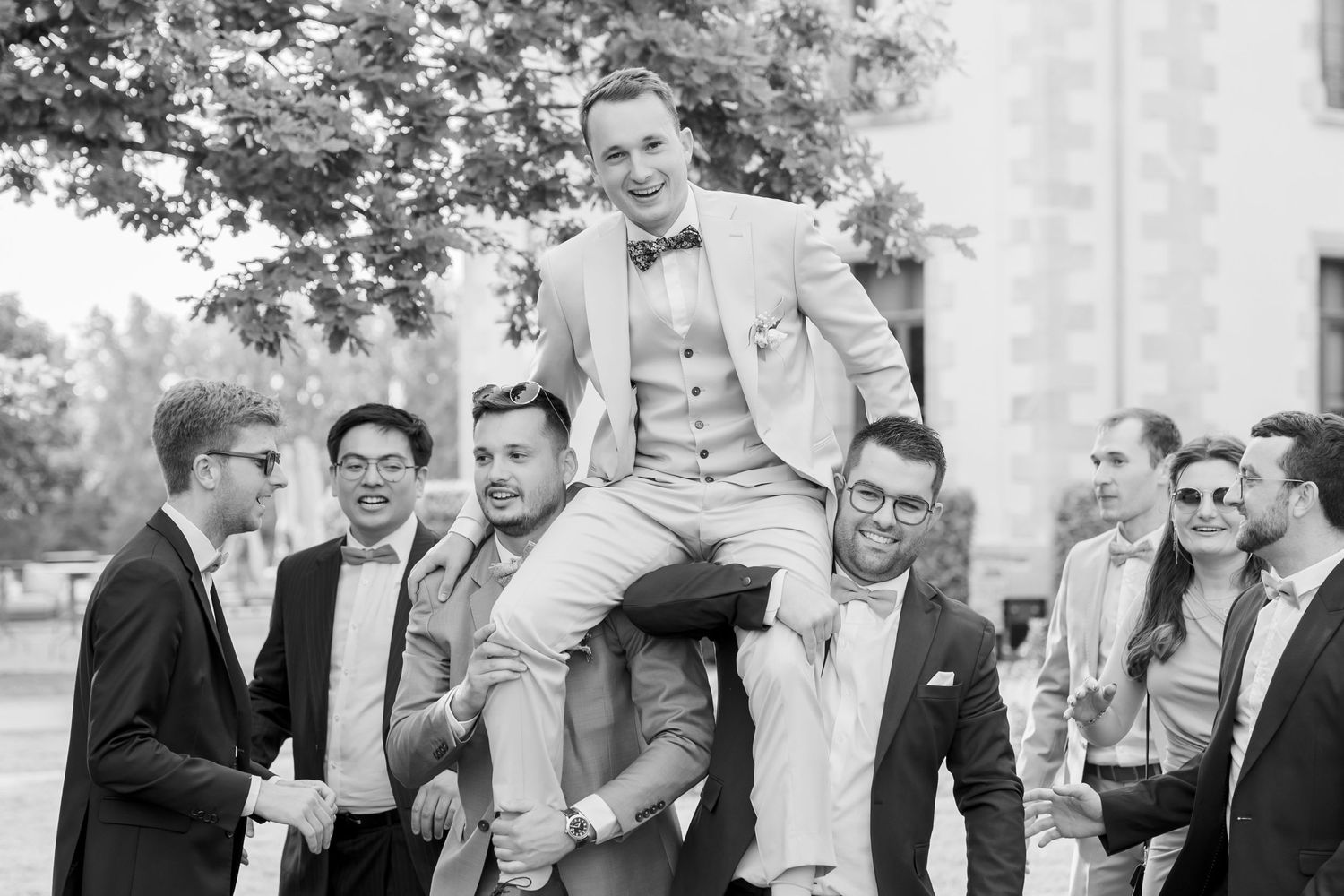 Black and white photos capture groomsmen's candid moments and laughter at outdoor wedding.