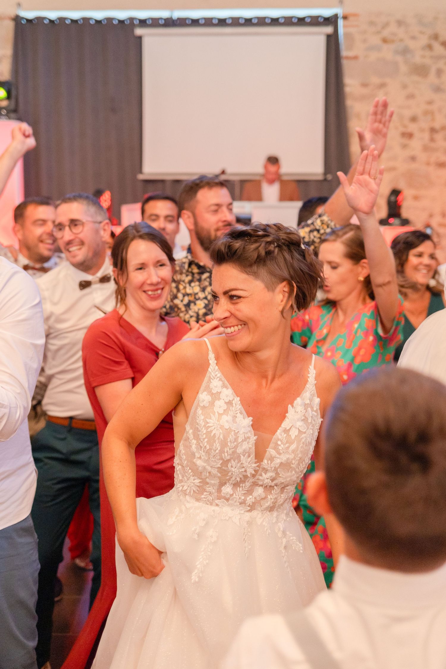 Wedding reception scene showing joyful dancing and celebration in a rustic stone-walled venue.