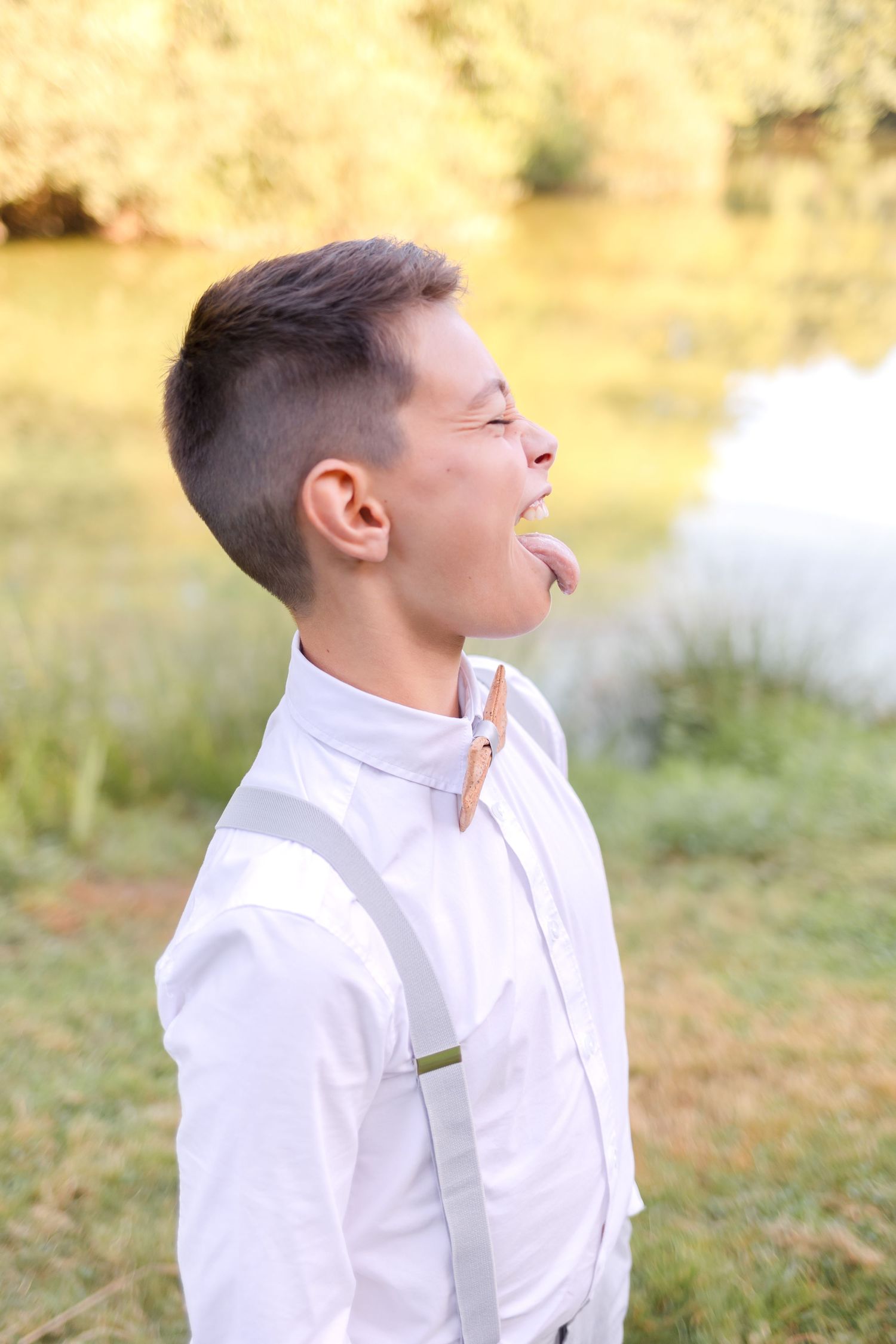 Joyful candid moment outdoors in white dress shirt with suspenders.