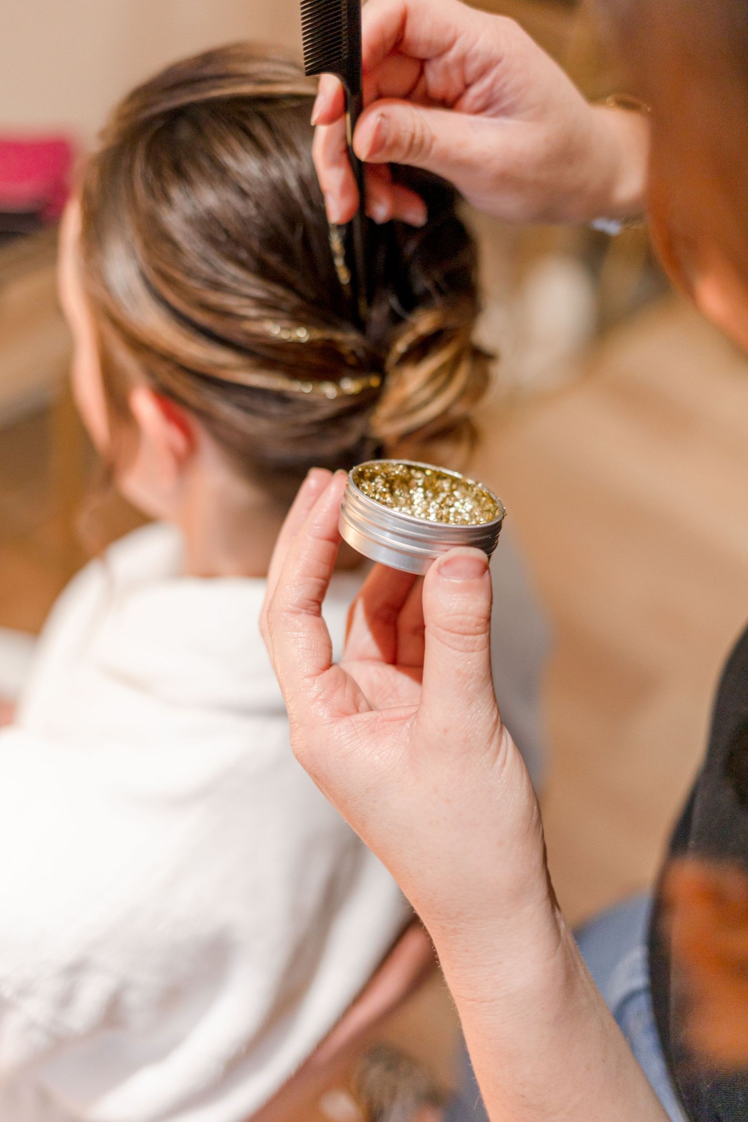 Hands placing a decorative gold hair accessory for bridal styling.