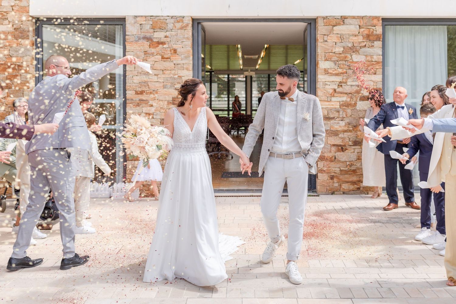 Wedding party celebrates on the steps of a rustic brick venue.