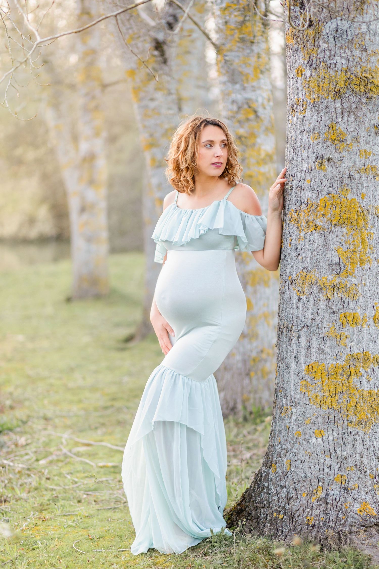 Beautiful maternity portrait against a birch tree wearing a flowing pale blue dress.