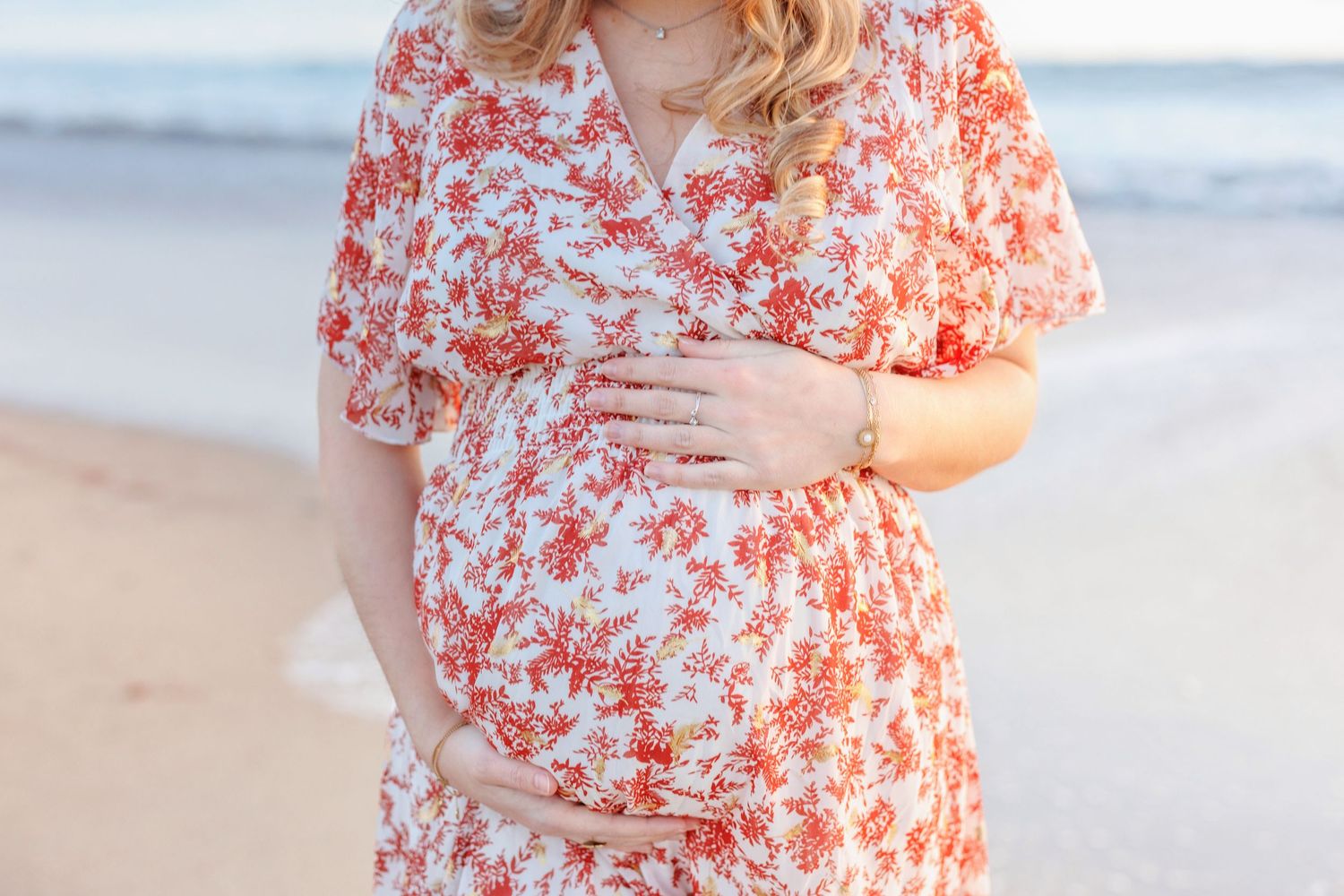 A close-up shot of a floral dress against a beach background during sunset.