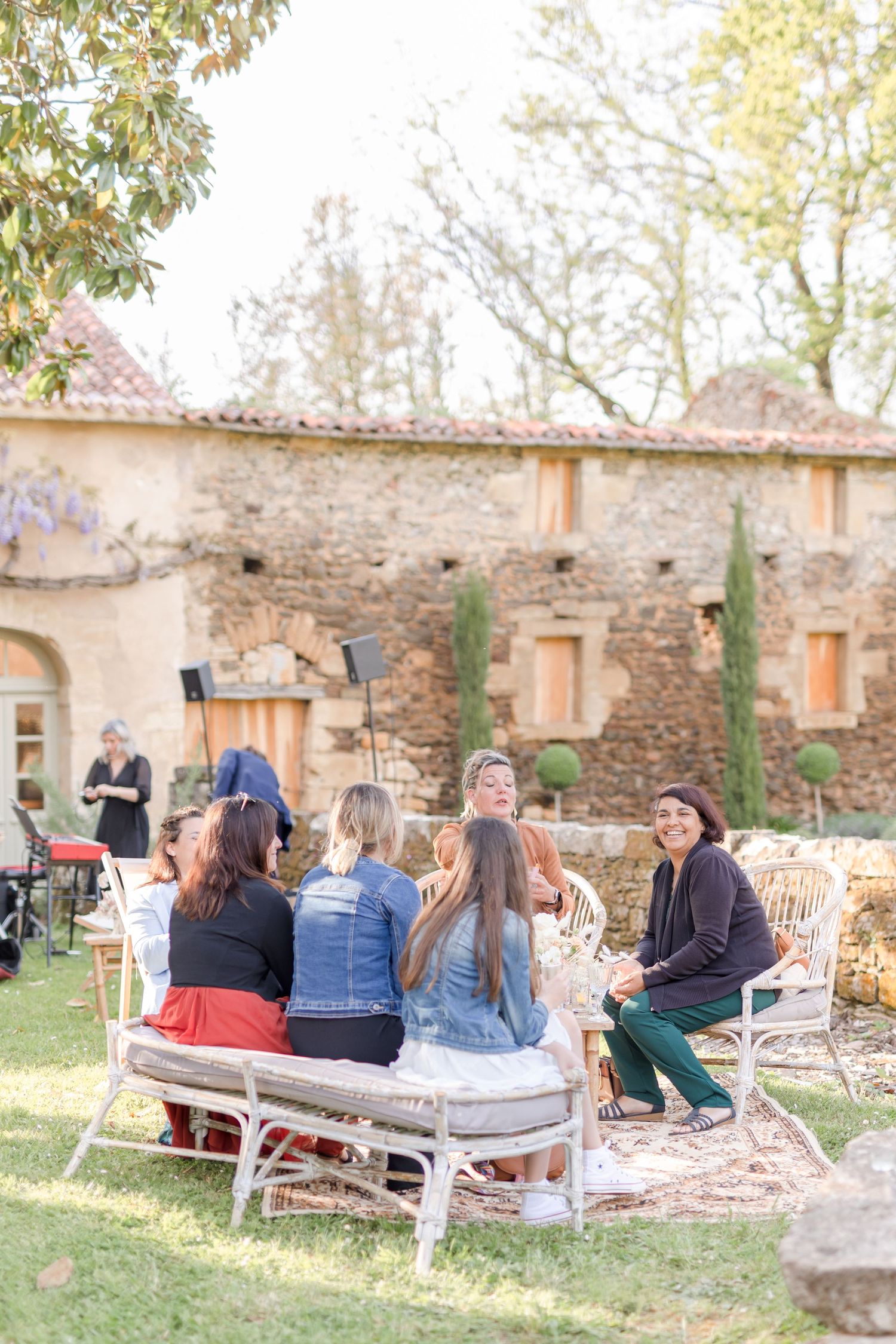 Group sitting on white outdoor furniture during a garden gathering.