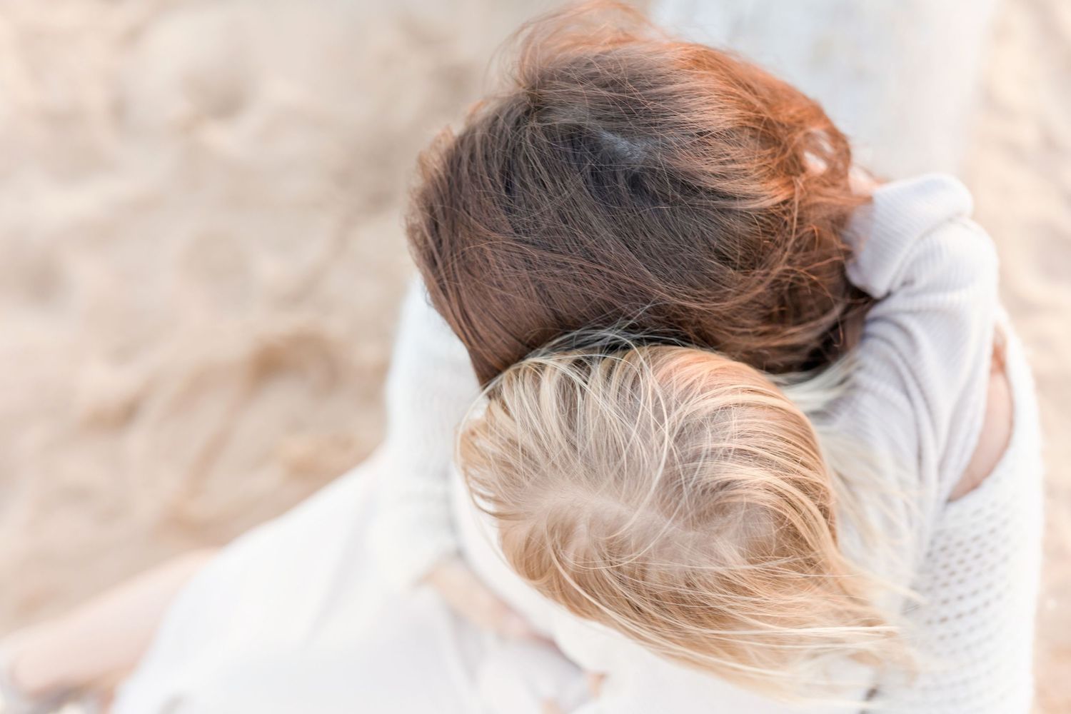 Close-up of two people embracing in warm sunlight on the beach.