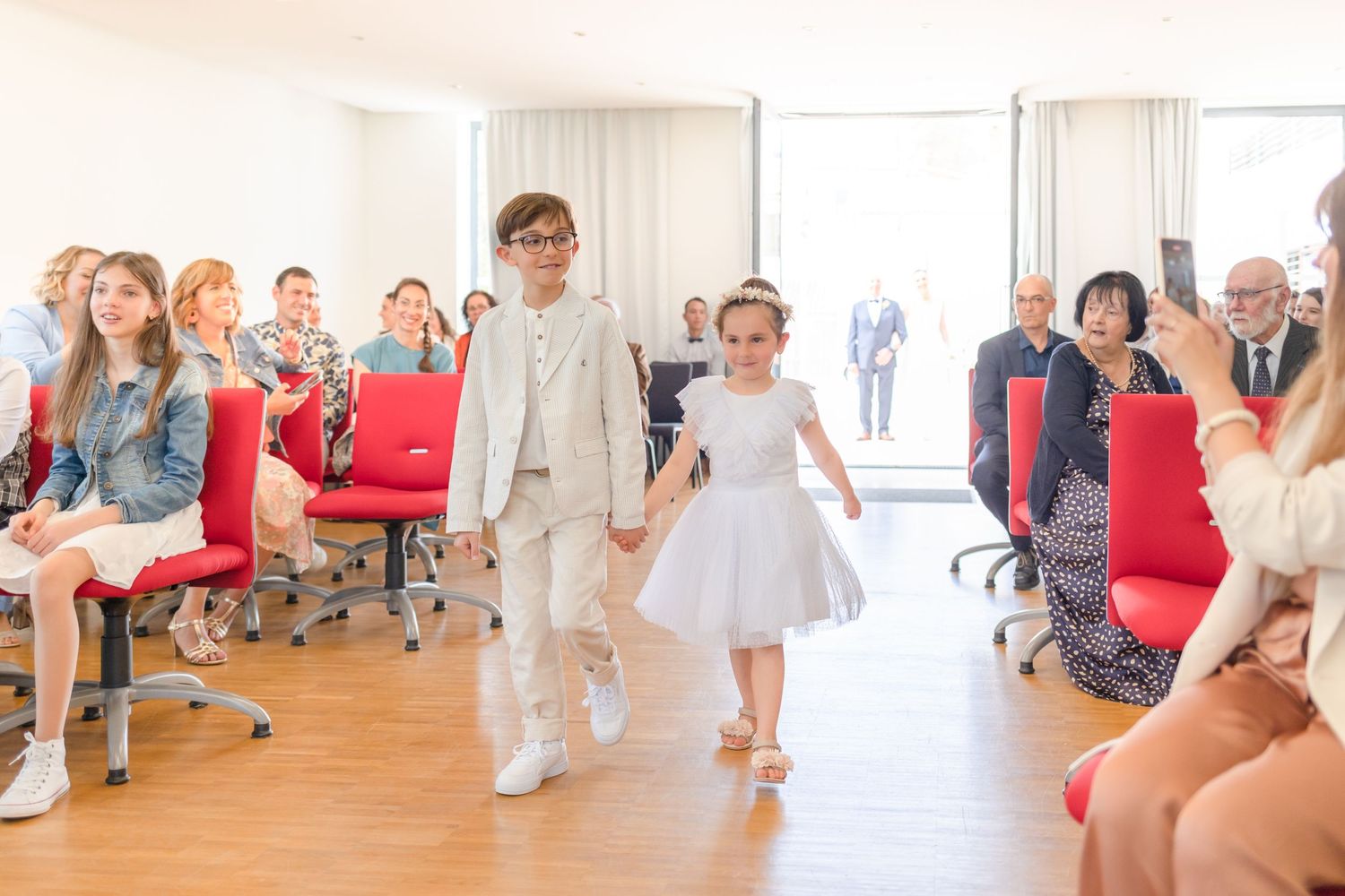Wedding celebration in bright modern venue with guests watching ceremony proceedings.