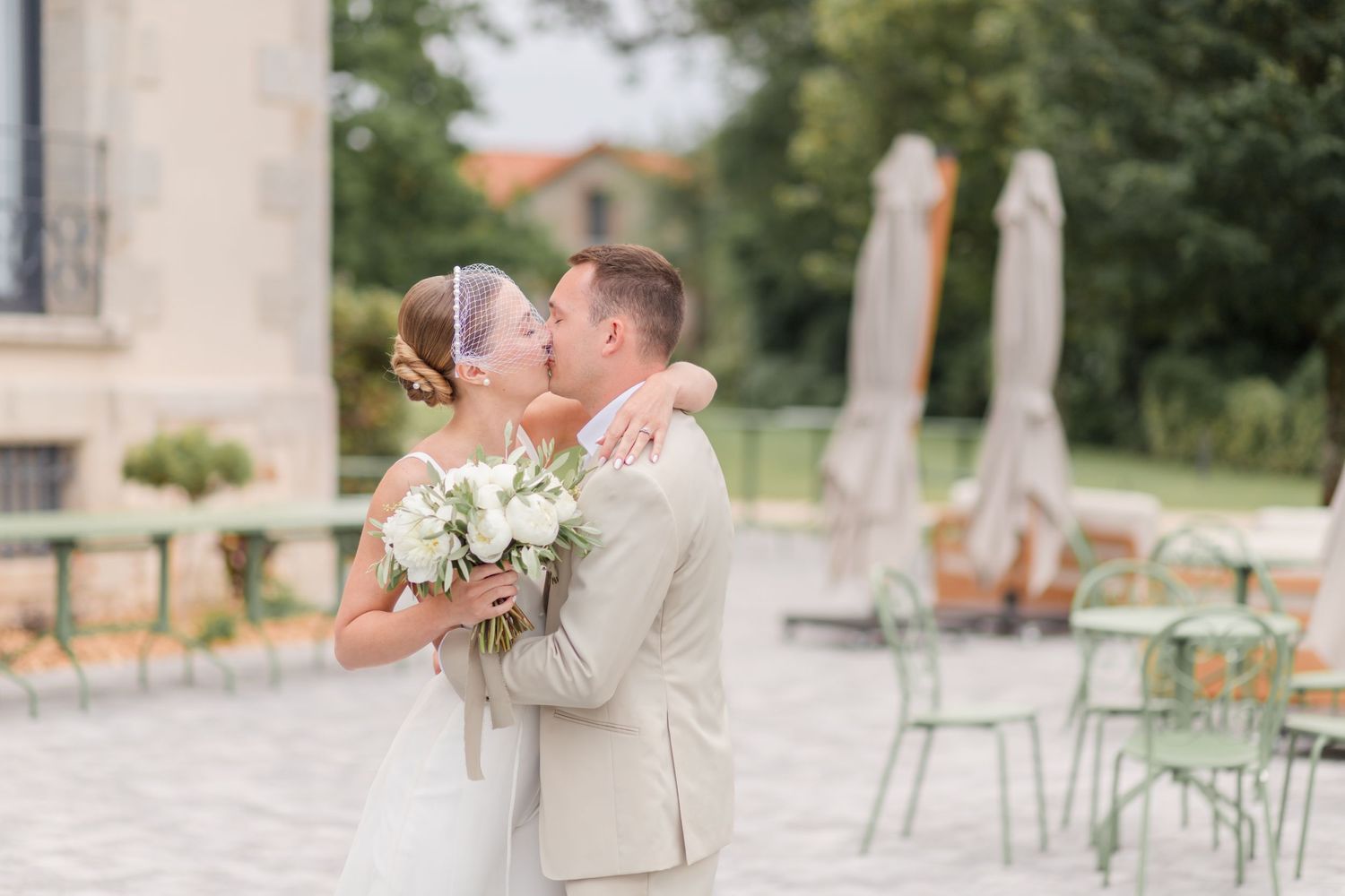 Wedding party walking together on cobblestone path near pastel colored European buildings.