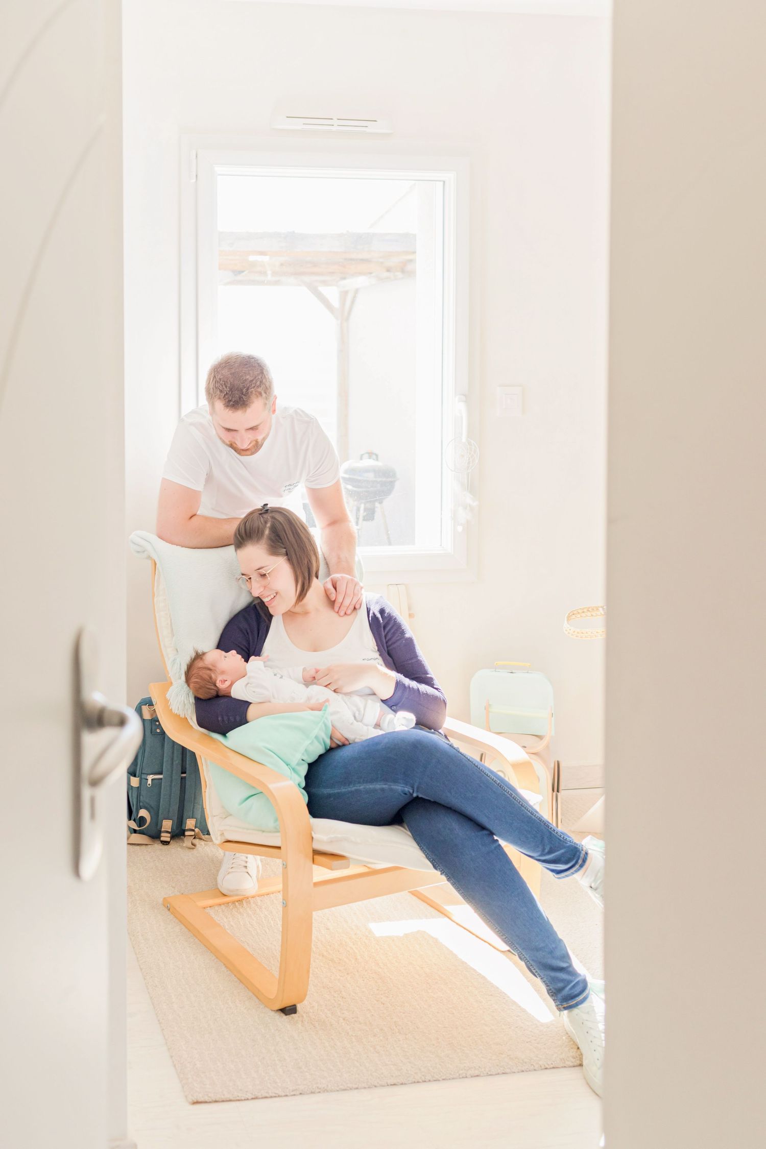 Family sharing intimate moment with baby in bright nursery room.