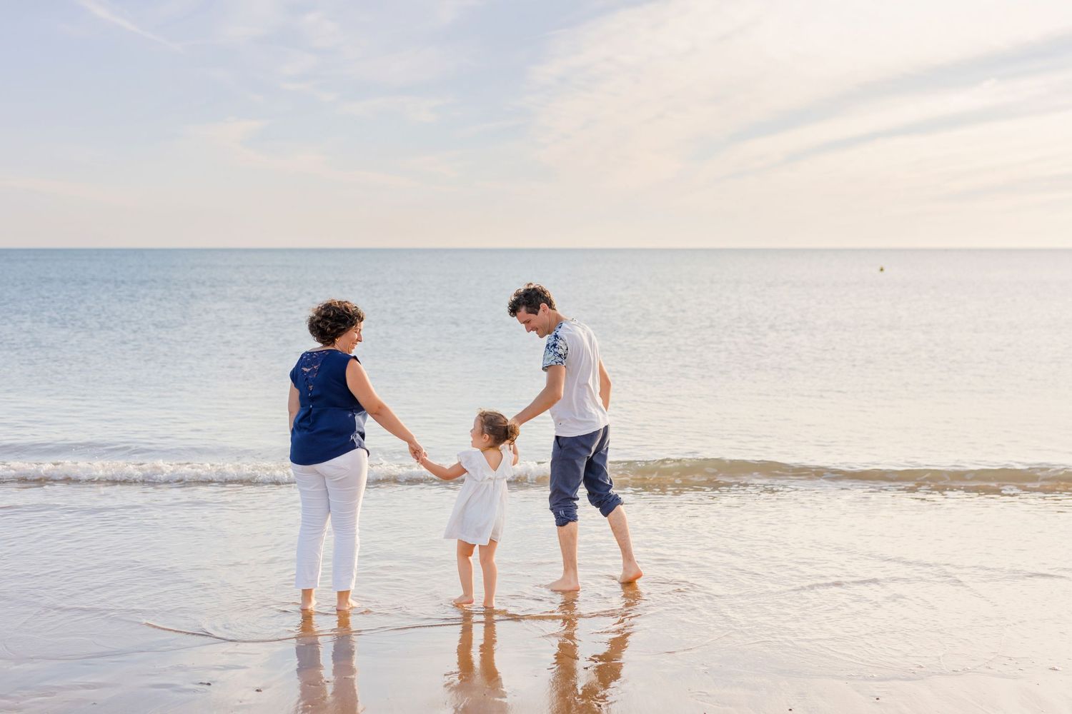 Family enjoying time together while walking along the water's edge at the beach.