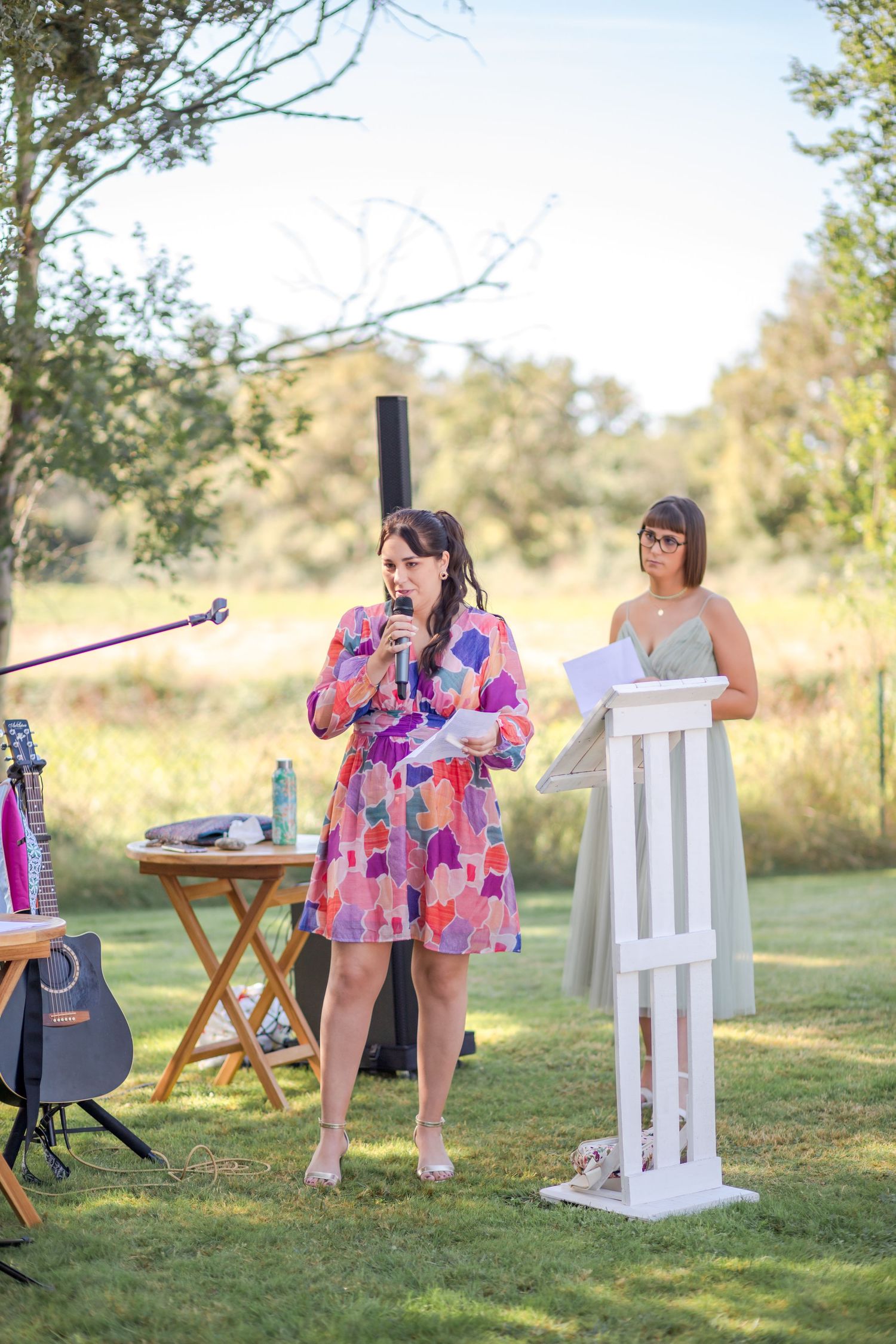Musicians performing at outdoor wedding with colorful decor and natural backdrop.
