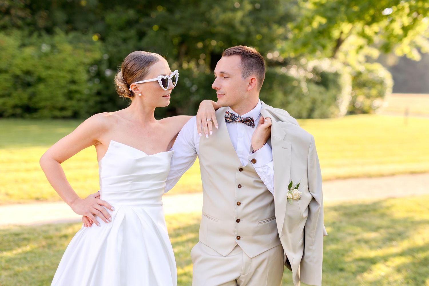 Newlyweds share intimate moment on sunny castle lawn.
