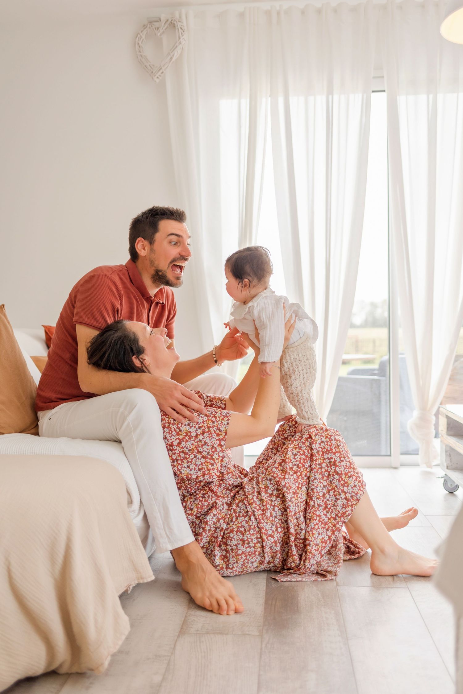 Happy family playing together on white furniture in a bright sunlit room.