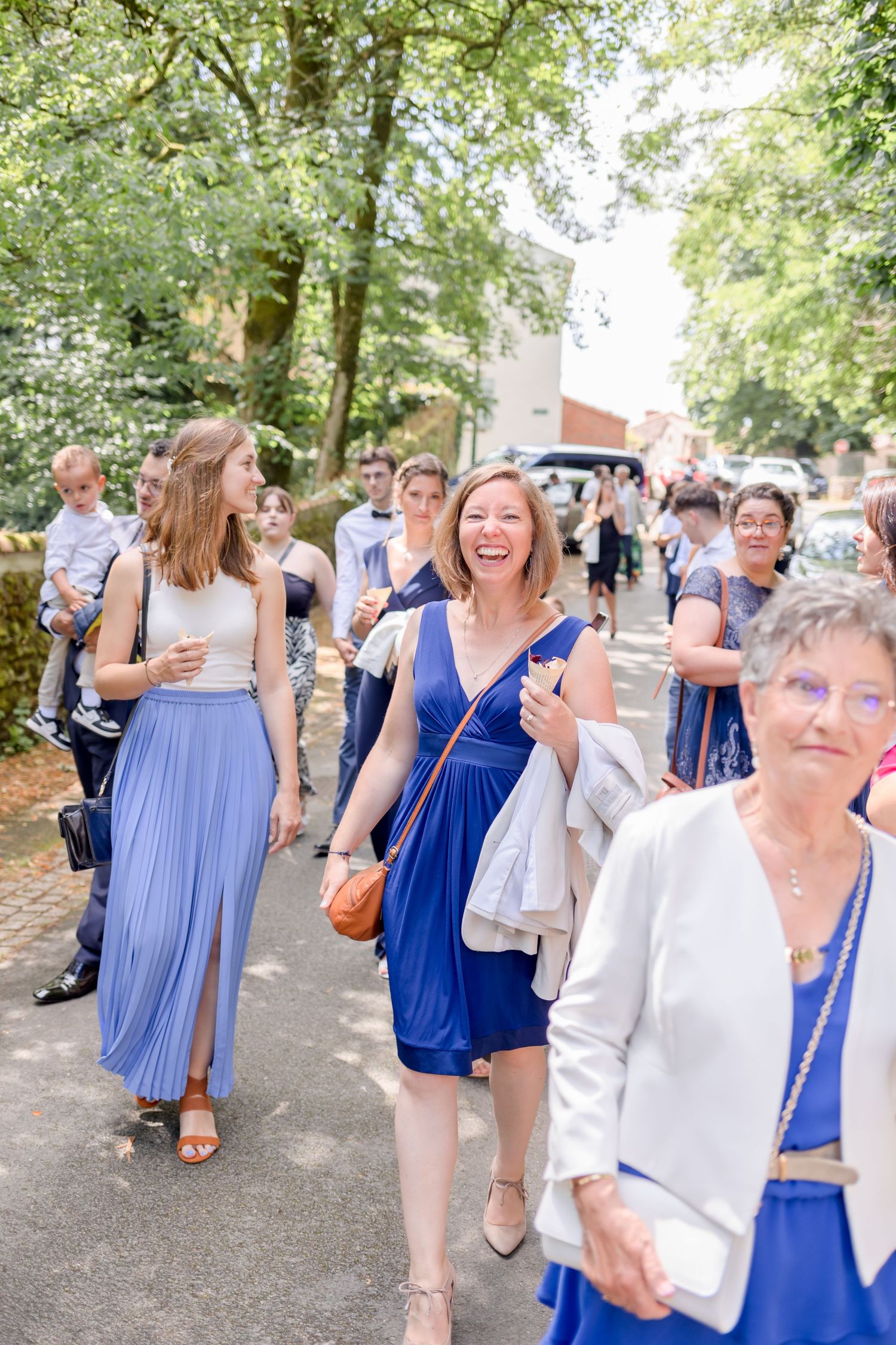 Wedding guests in blue dresses enjoying outdoor summer celebration.