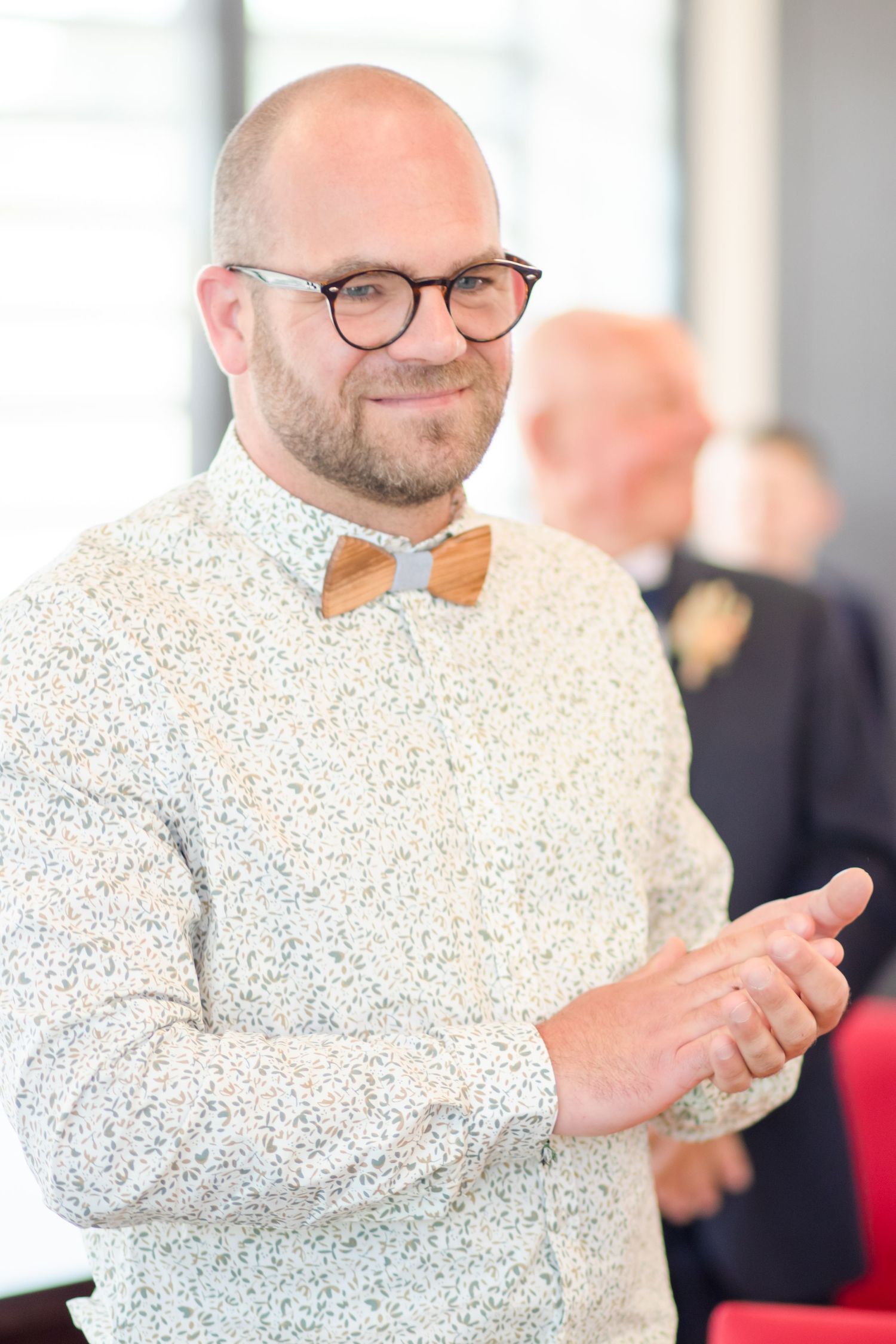 Person in a polka dot shirt and bow tie clapping during a celebration.