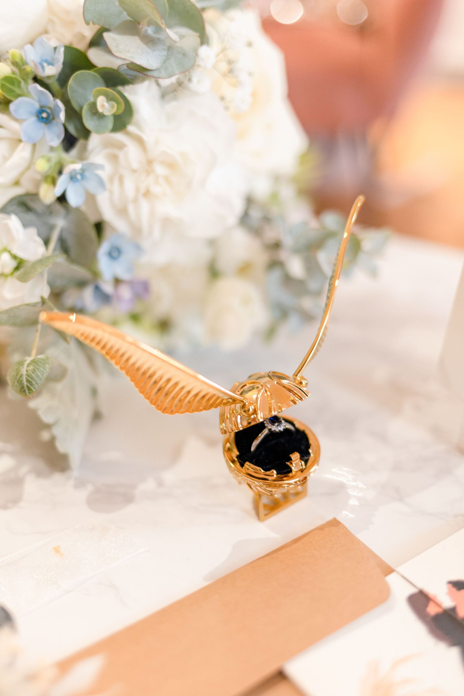 Golden snitch decoration among blue and white floral arrangements.