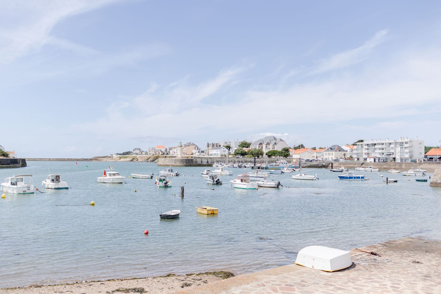 Scenic coastal harbor view with boats anchored in calm blue waters on a sunny day.