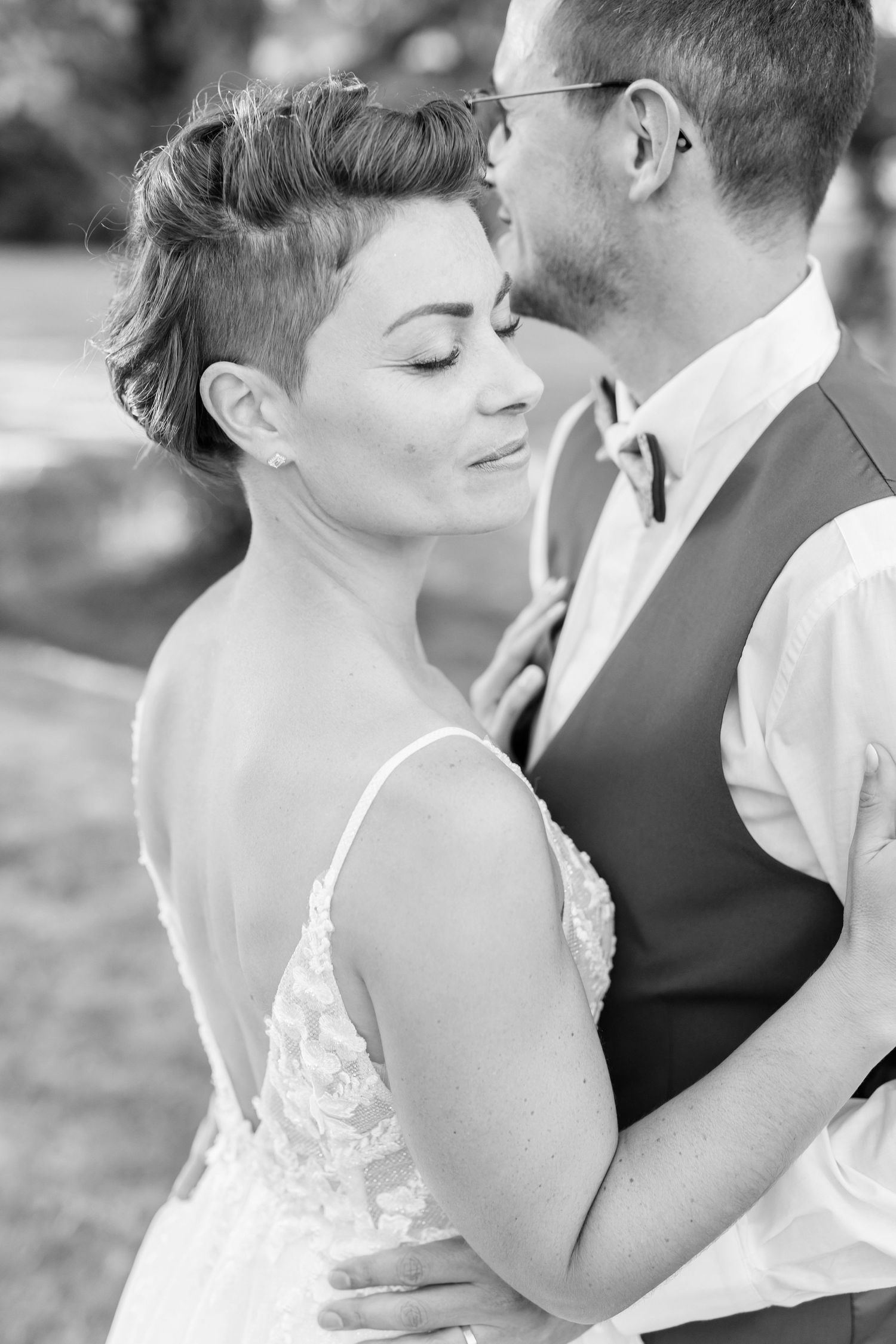 Black and white intimate wedding portrait showing tender moment between newlyweds.