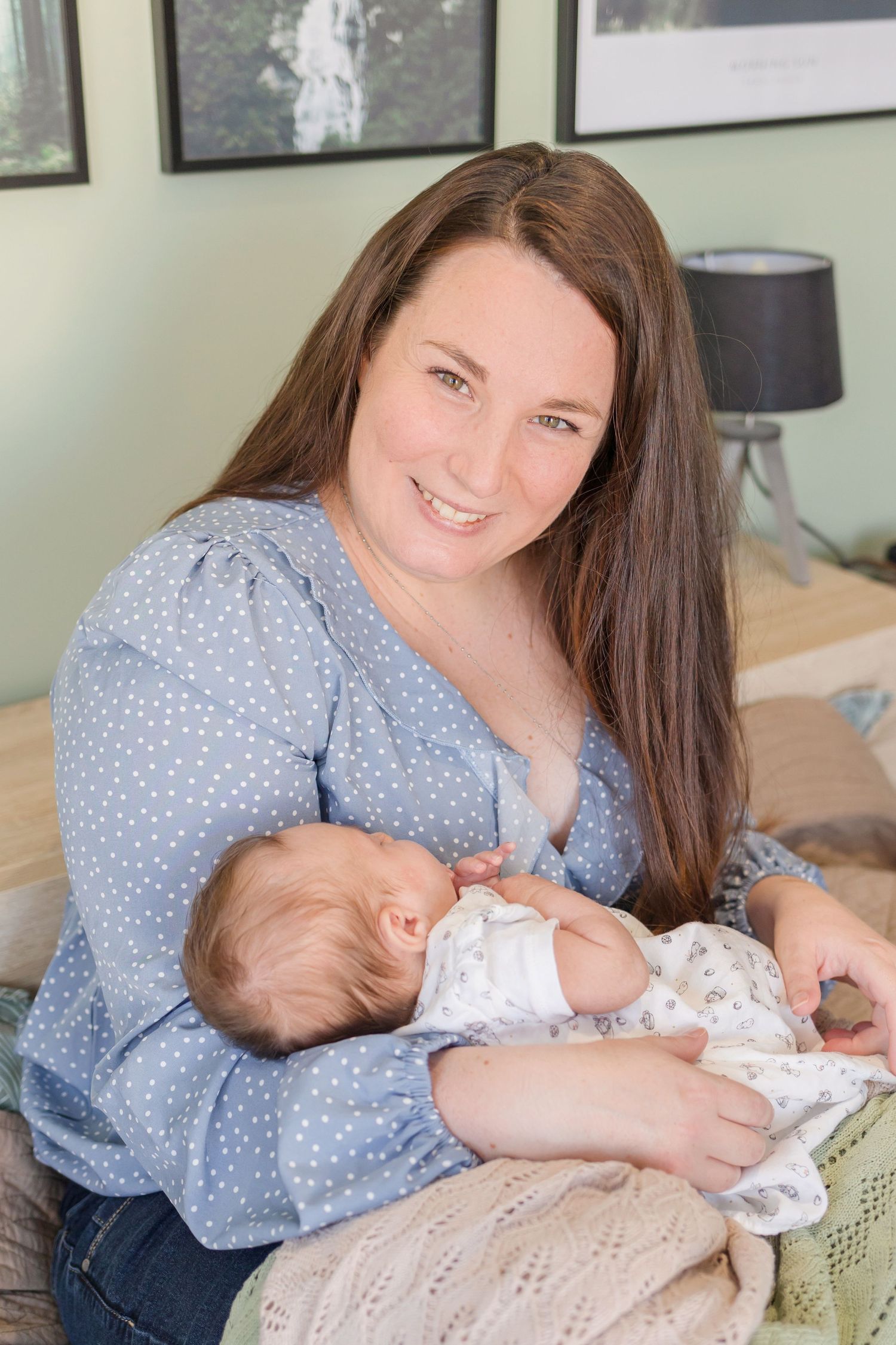 Tender moment of parent cradling sleeping baby on couch with green wall background.