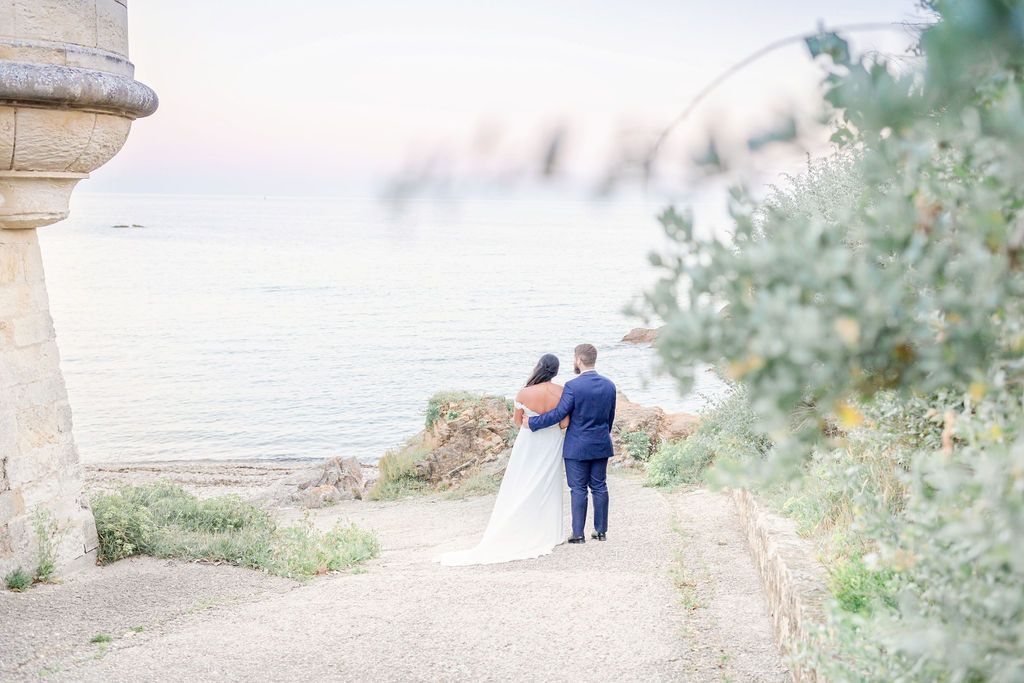 A romantic wedding photo captured on a coastal path with soft dreamy lighting.