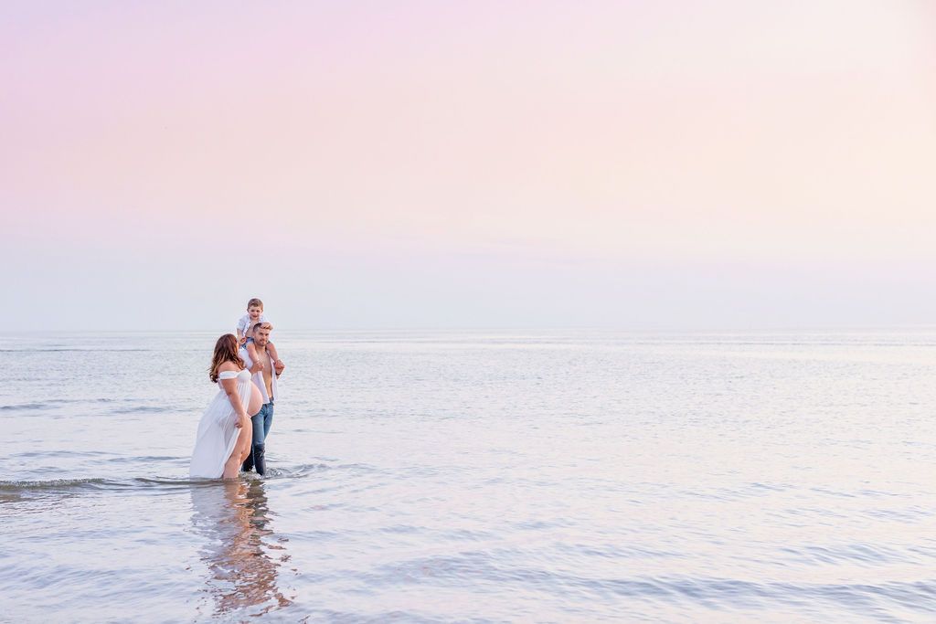 Couple embracing during sunset photoshoot in shallow ocean waters.