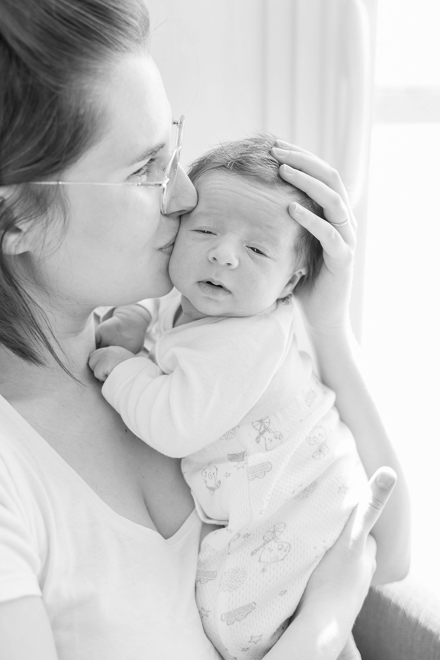 Black and white portrait series showing tender moments between a parent and infant.
